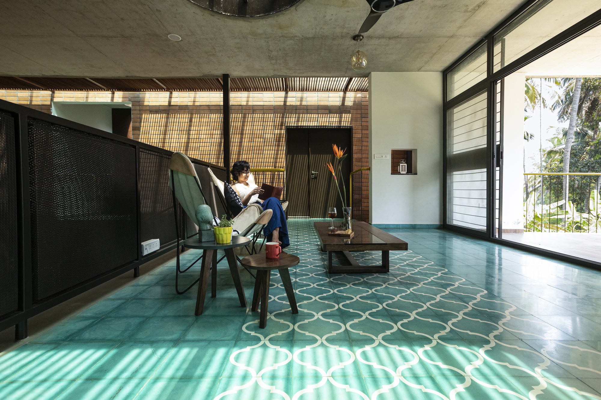 Upper floor sitting area with patterned turquoise tiles and a person reading by the window