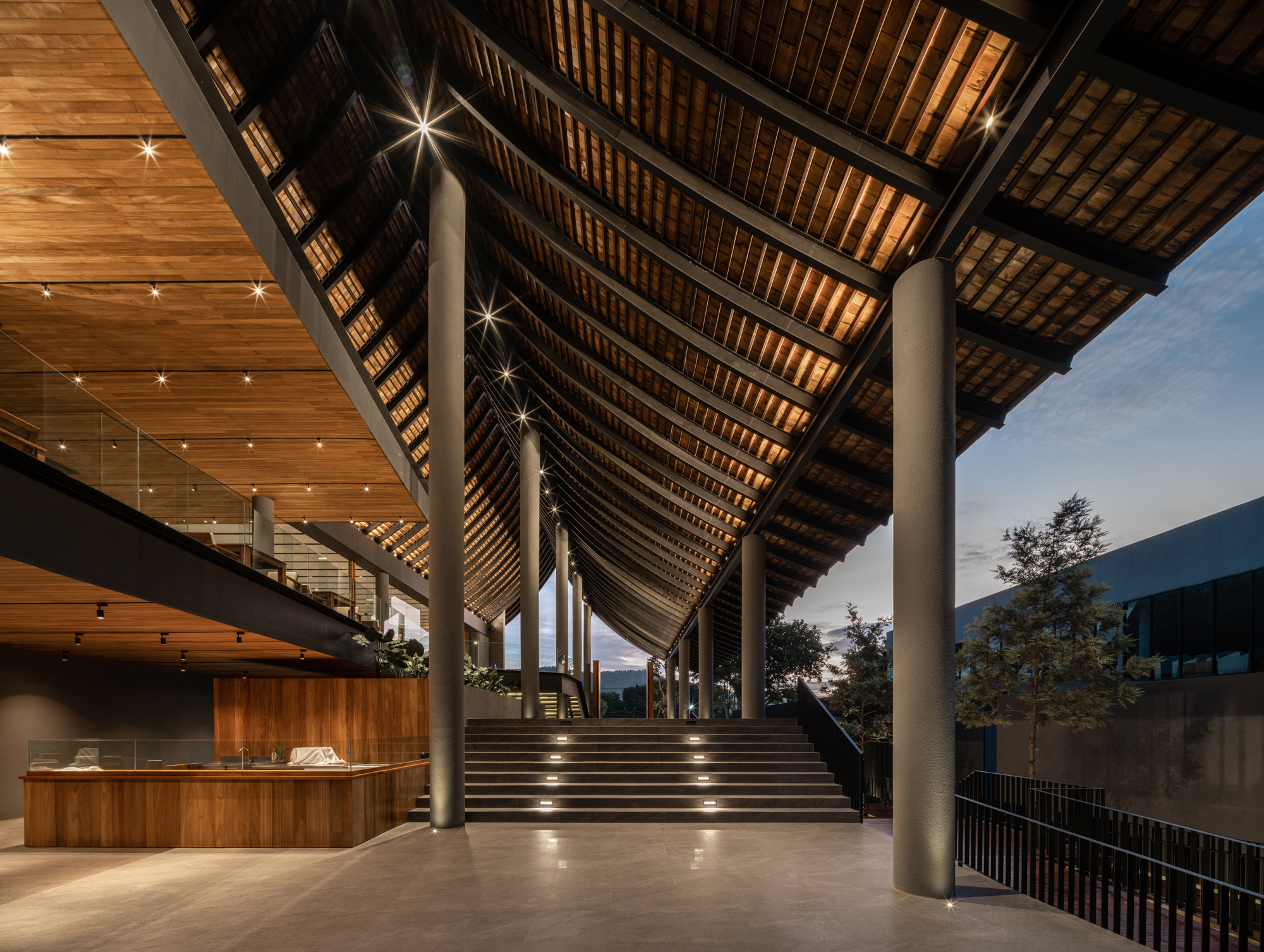 Covered entrance staircase with exposed timber rafters and cylindrical columns at dusk