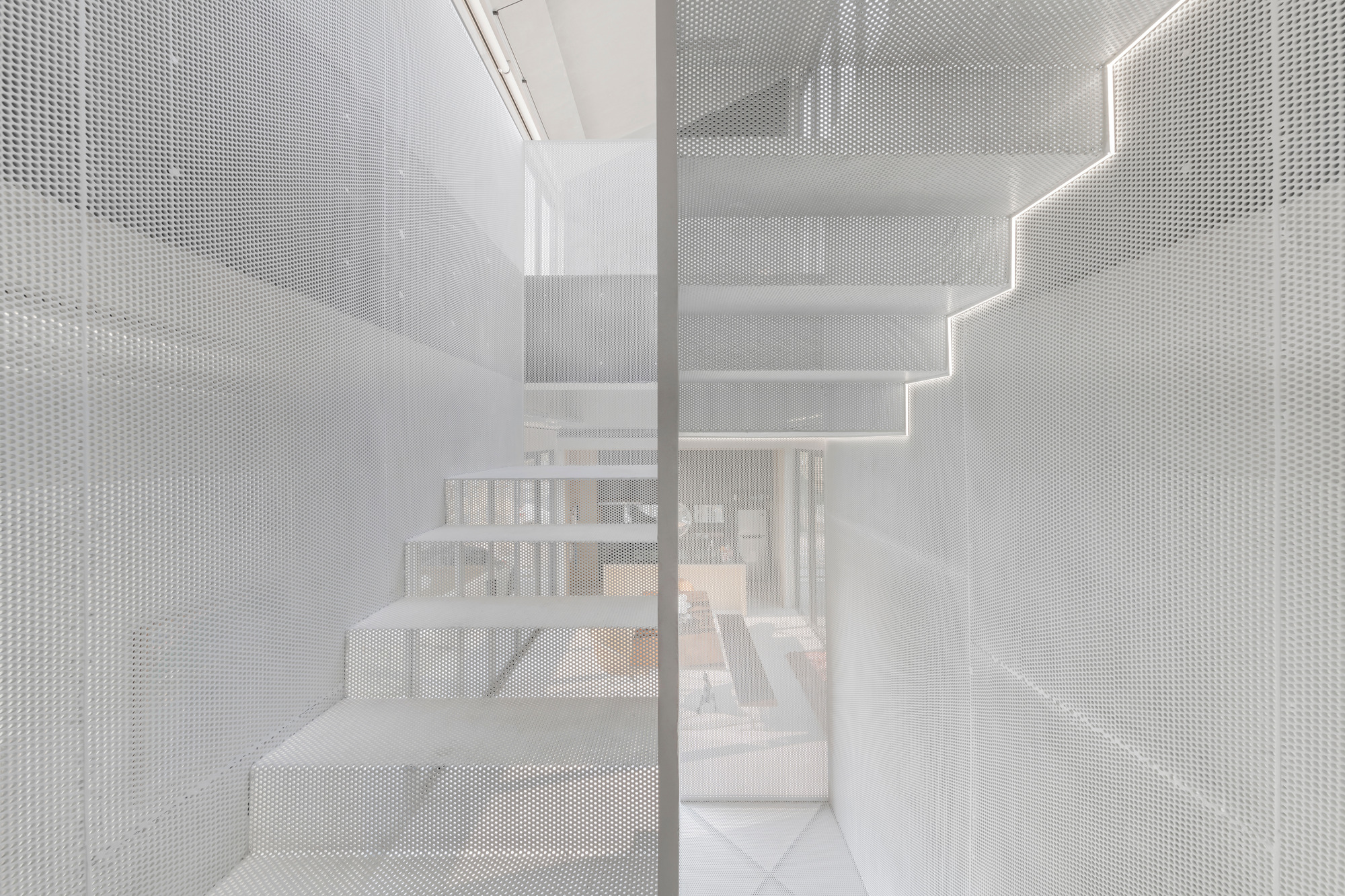 View through translucent perforated metal stair enclosure revealing the dining area beyond