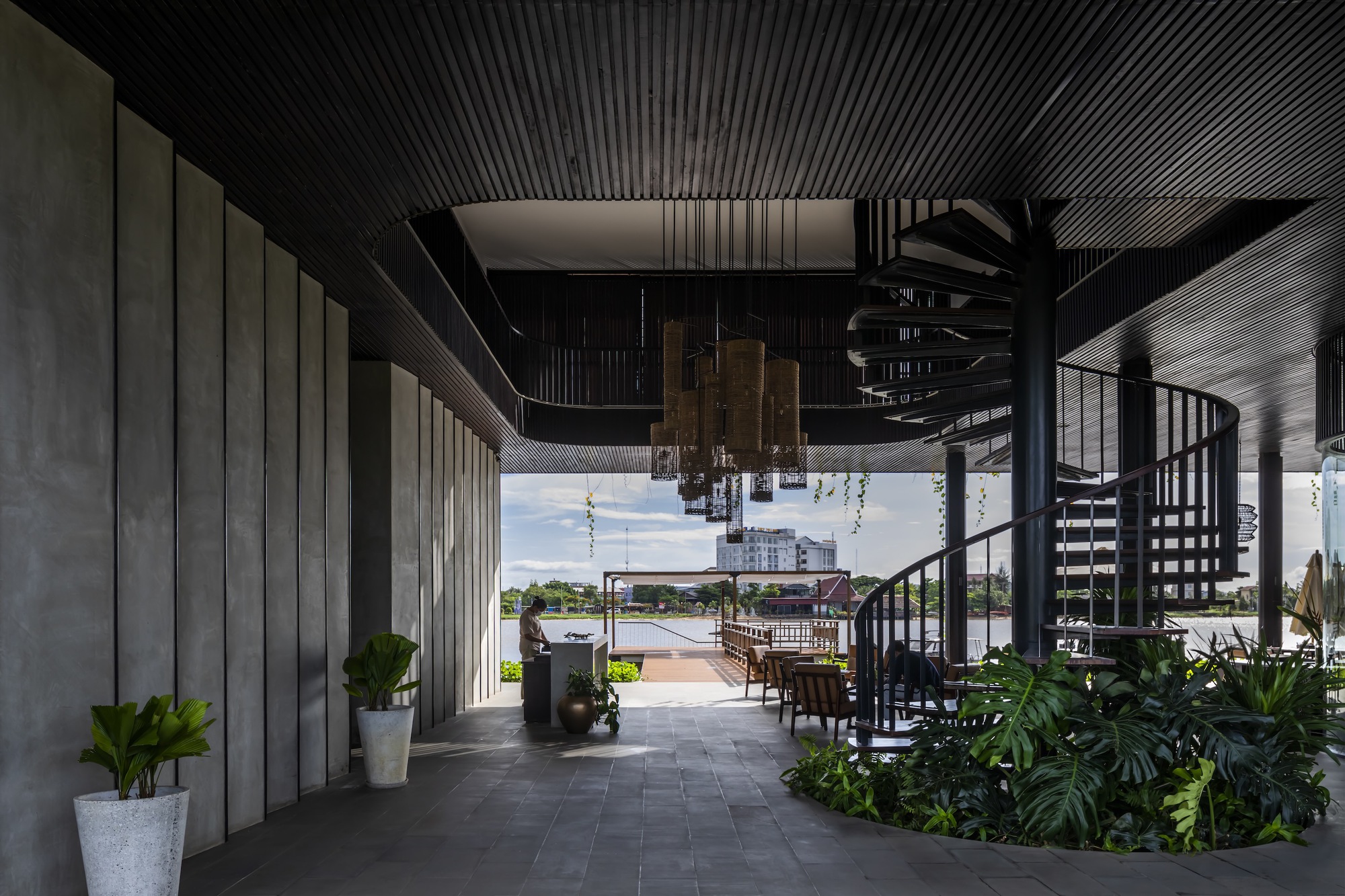 Covered terrace with spiral stair and slatted ceiling overlooking the waterway