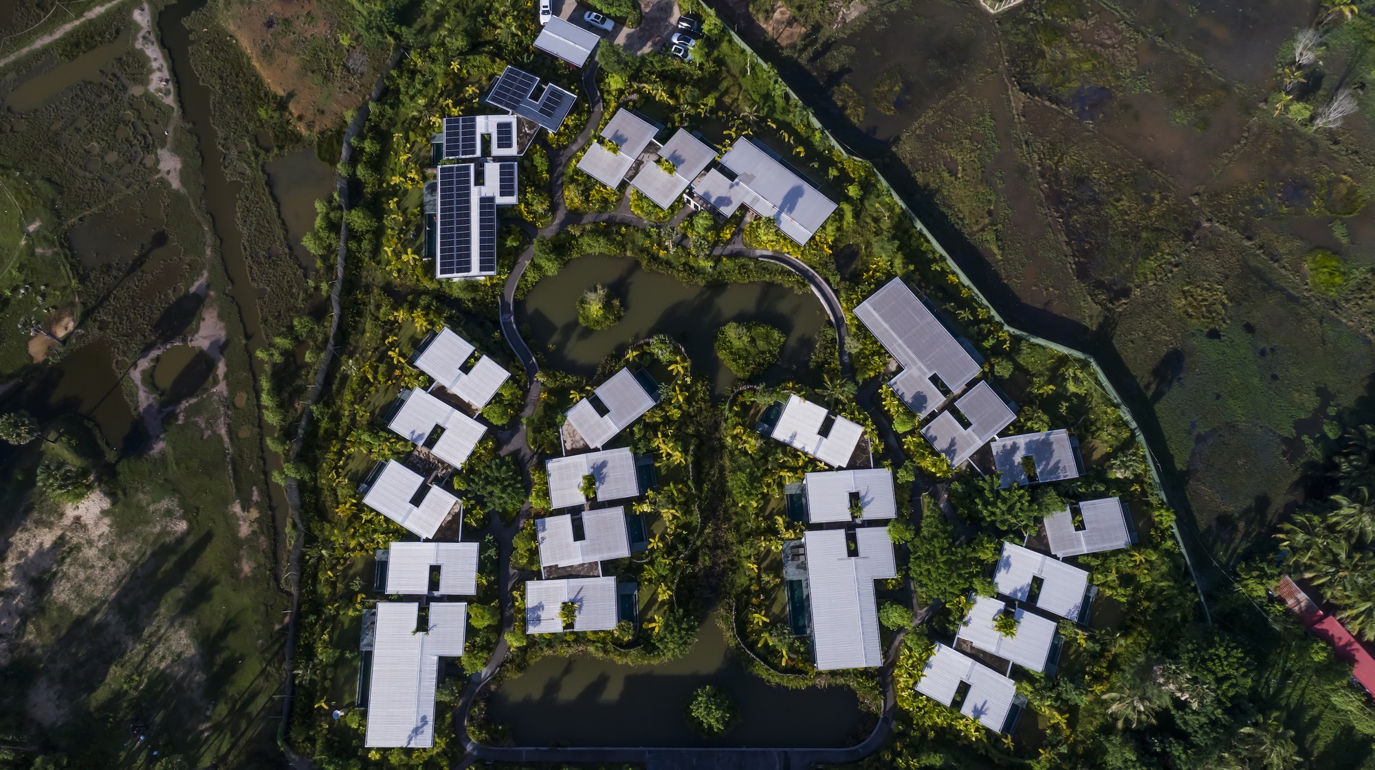 Top-down view of the curving cluster of white-roofed villas arranged around landscaped courtyards and pathways
