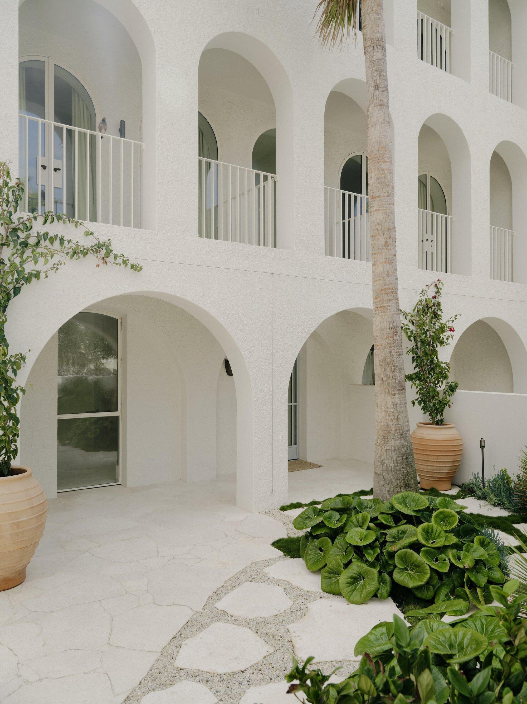 Interior courtyard with arched openings, terracotta planters, and gravel pathways beneath a palm tree