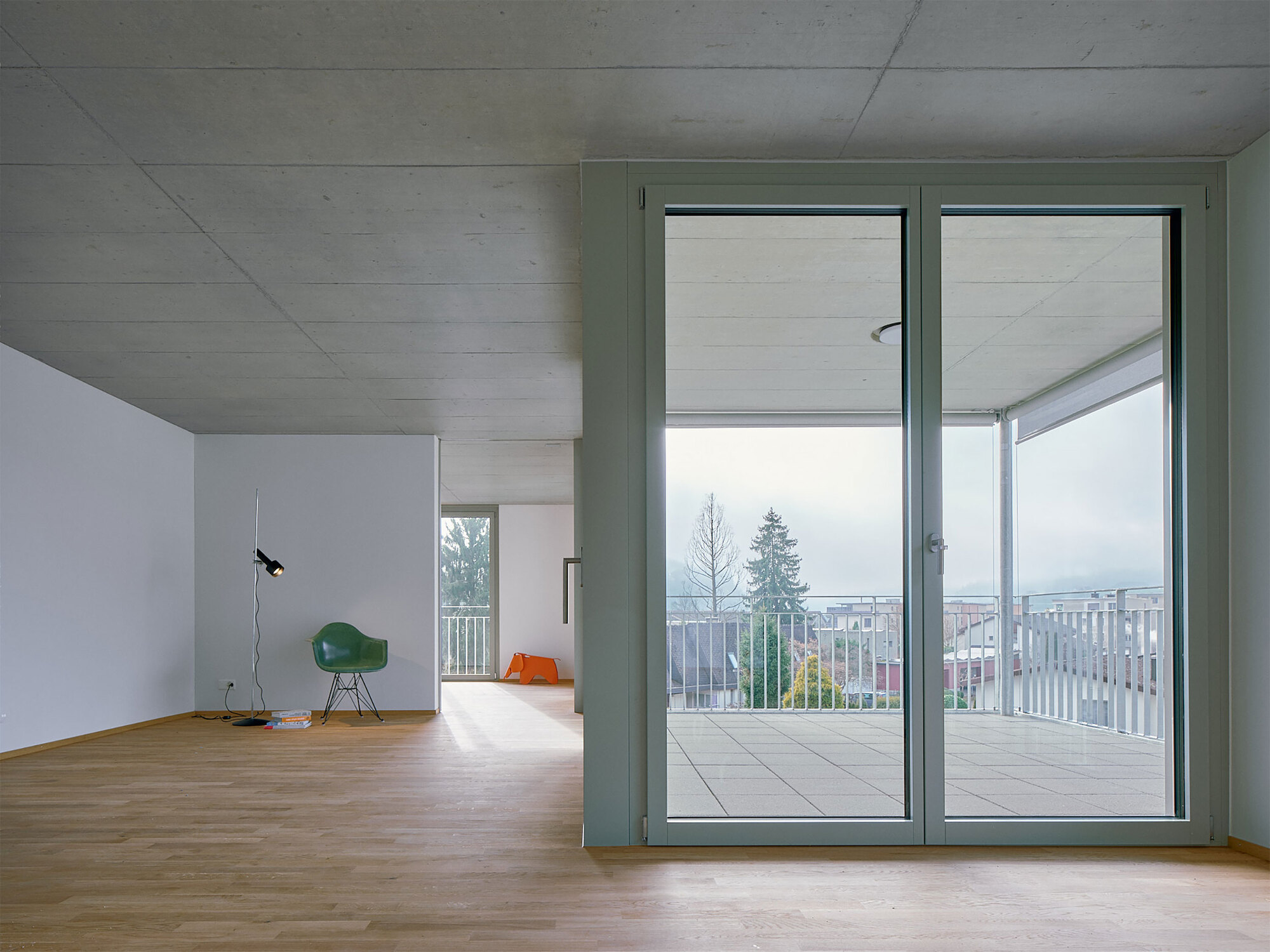 Interior living space with oak flooring and glass doors opening to the balcony under an overcast sky