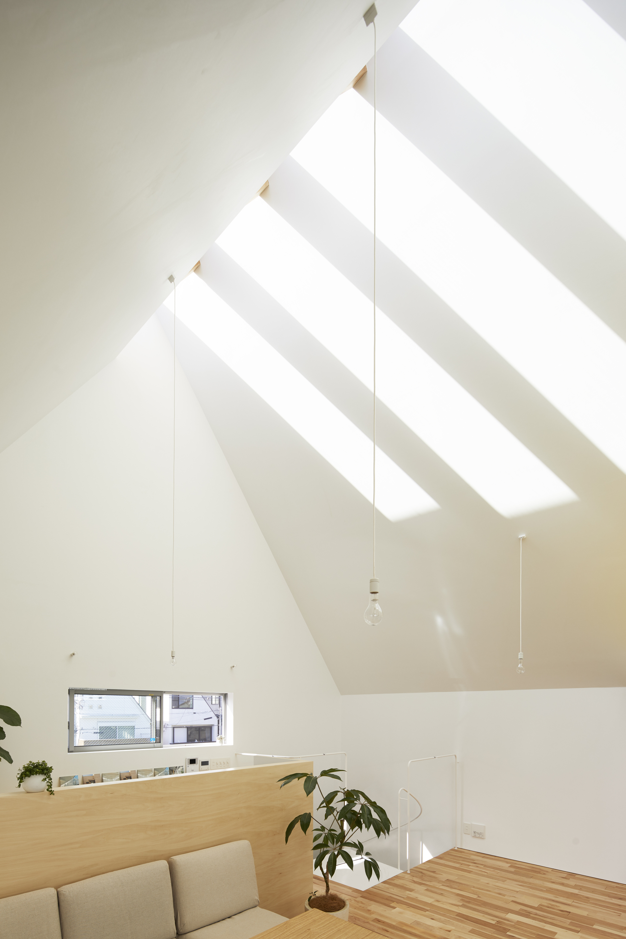 Pitched ceiling with exposed rafters and skylights casting diagonal shadows across white walls