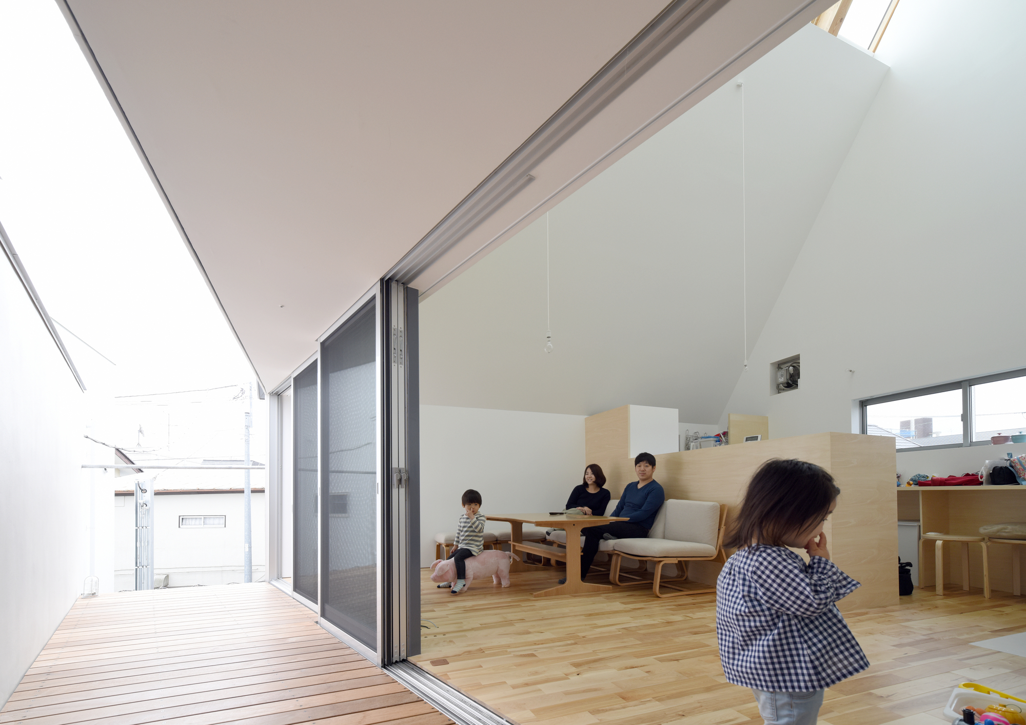 Living area opening to timber deck through sliding glass doors with family seated inside