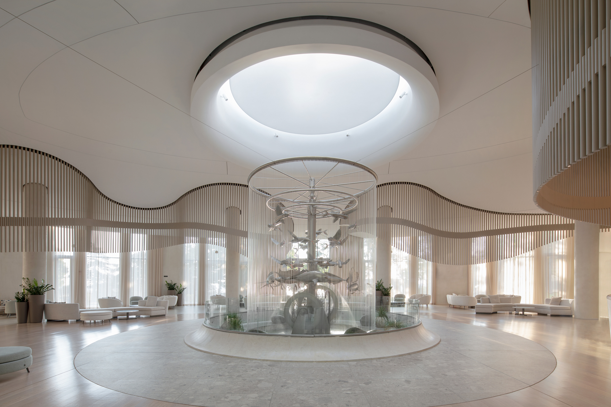 Circular lobby with central fountain beneath a ring skylight and undulating slatted screen
