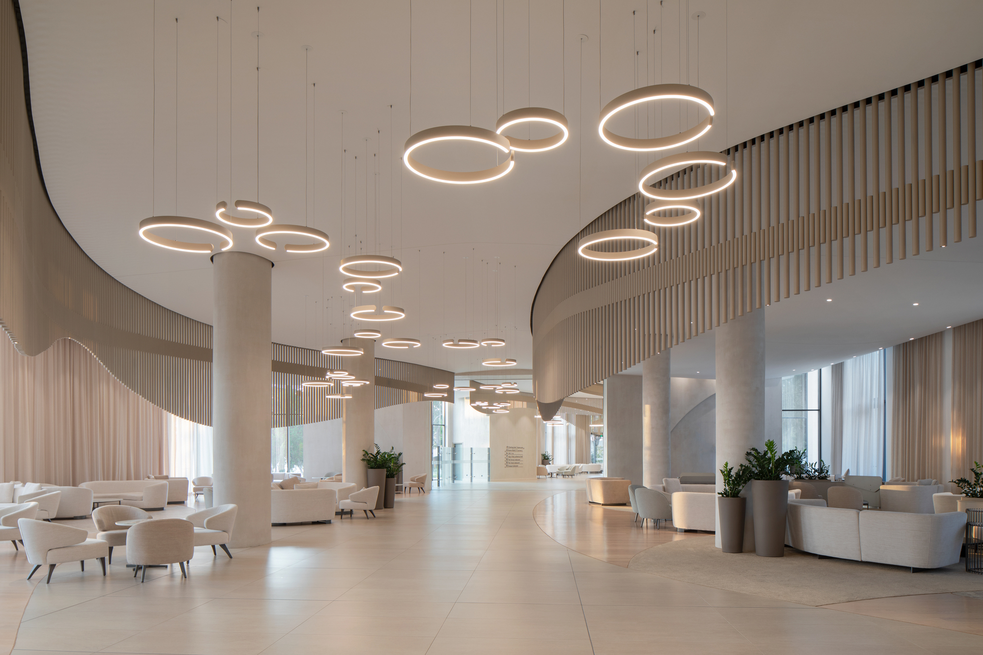 Lobby interior with circular ring pendant lights suspended from a curved soffit above cylindrical columns