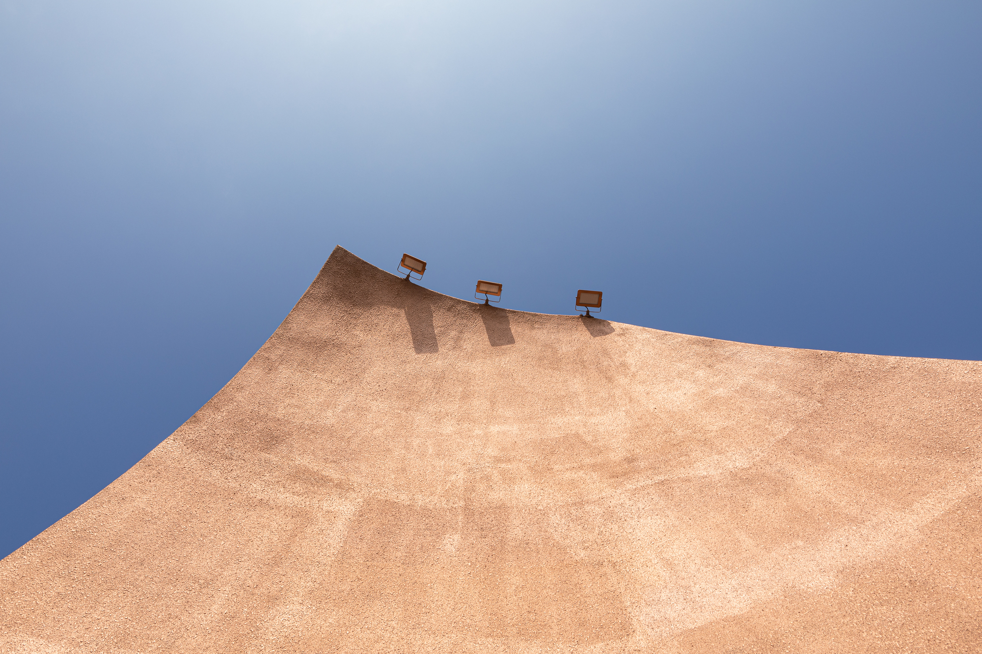 Angled copper facade wall with three roof vents against a blue sky
