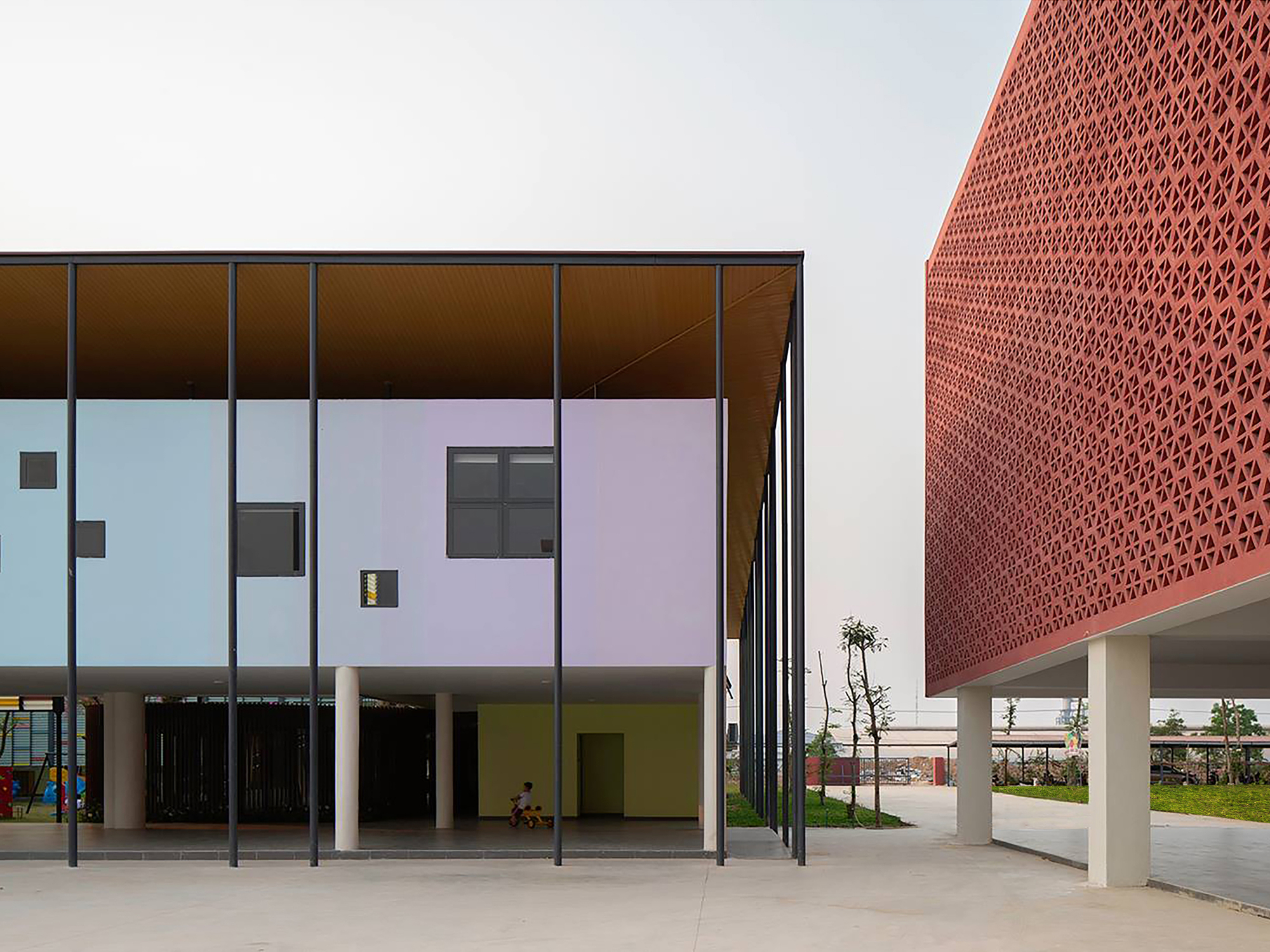 Corner view of the glazed colonnade with pastel panels and perforated terracotta screen volume beyond