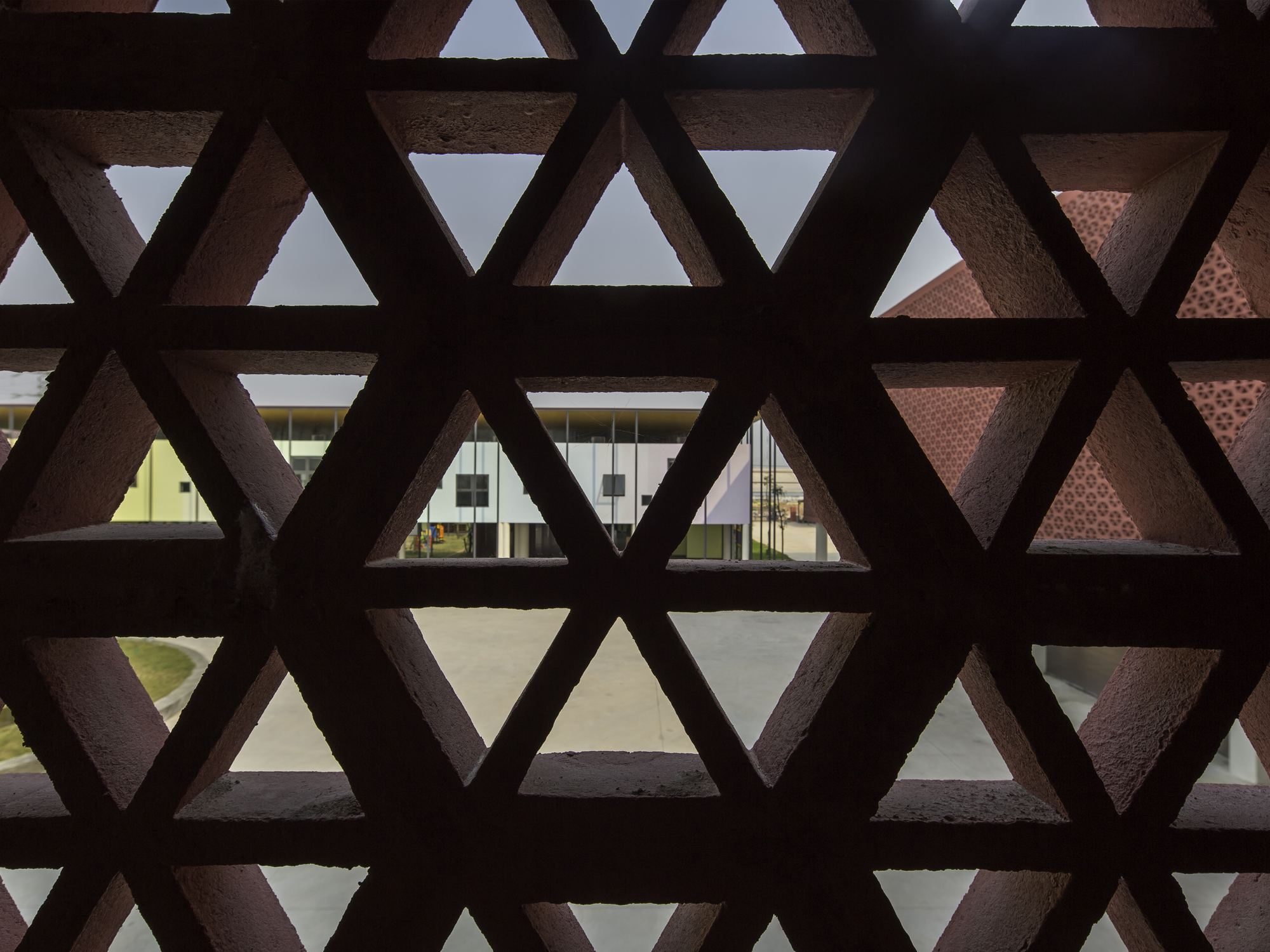 View through triangular lattice screen showing courtyard with another patterned facade beyond