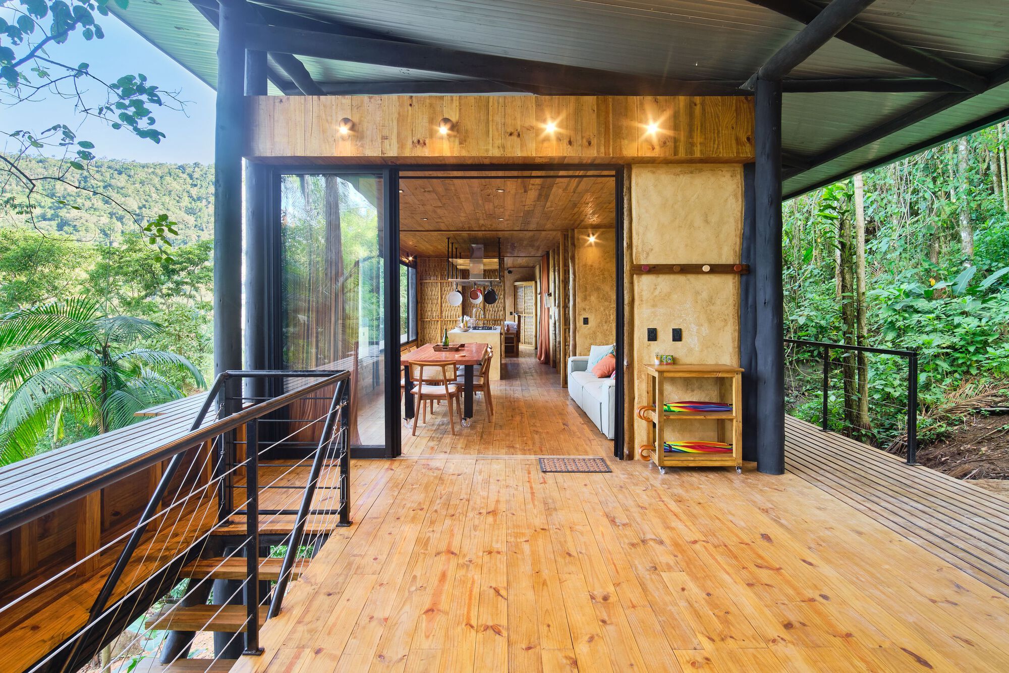 Covered deck with corner glazing and timber-clad ceiling opening to interior dining and living spaces