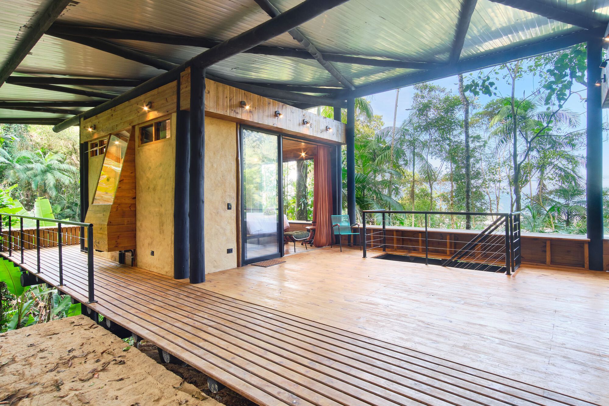 Covered timber deck with steel frame and plywood walls opening to tropical vegetation