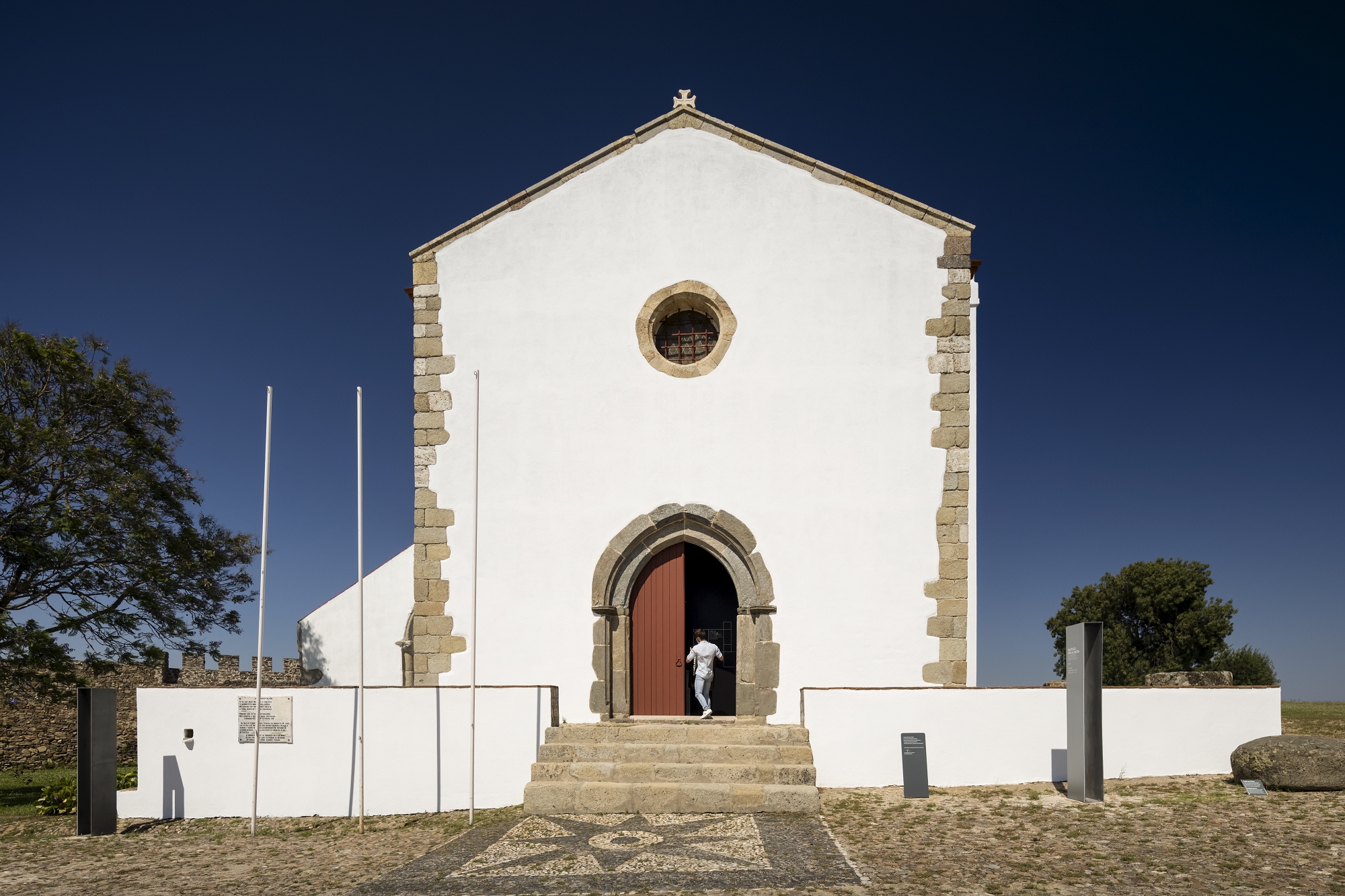 White facade with stone quoins and arched doorway under clear blue sky