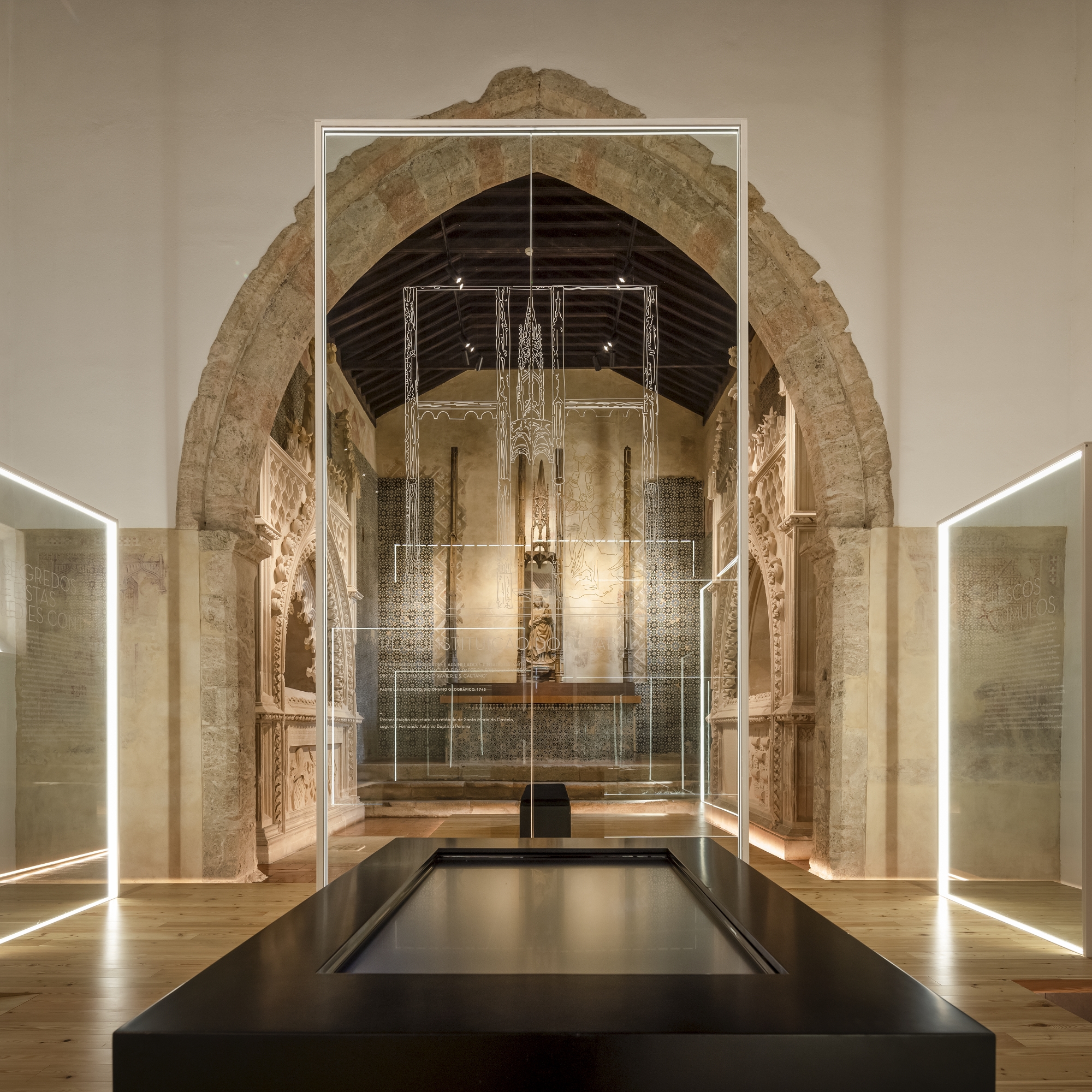 Stone archway framing nave with glass vitrines and timber ceiling at night