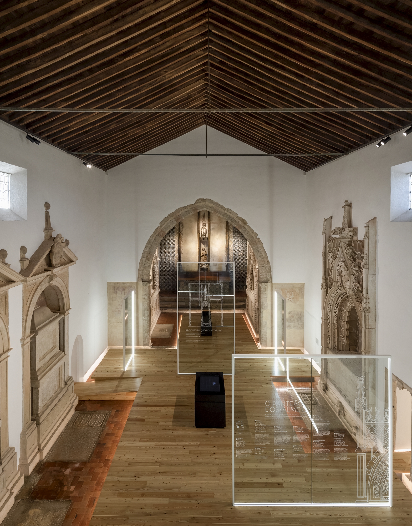 Gallery hall with exposed timber rafters and glass display cases on oak flooring