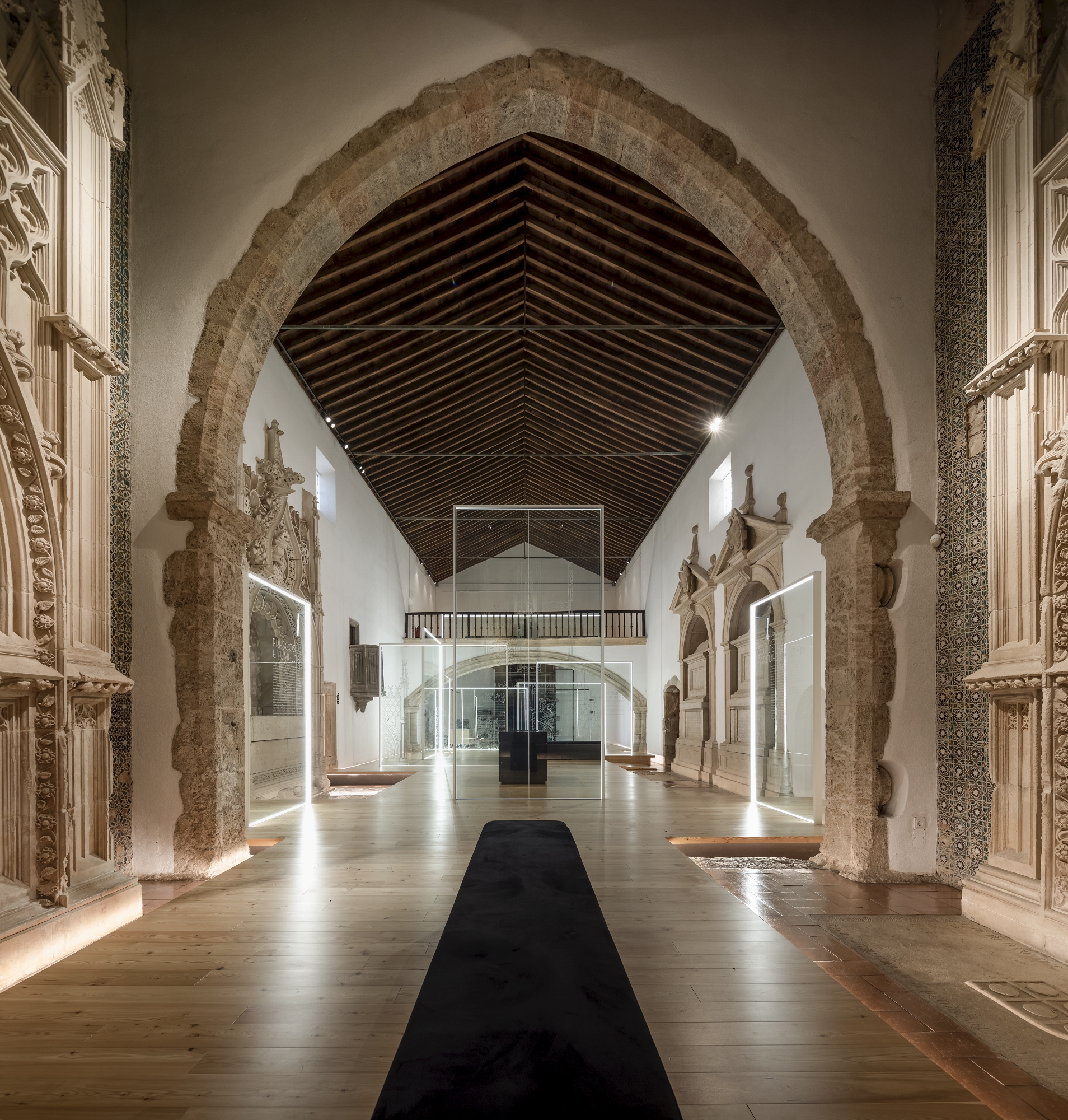 Central black carpet runner beneath pointed arch with timber battens overhead