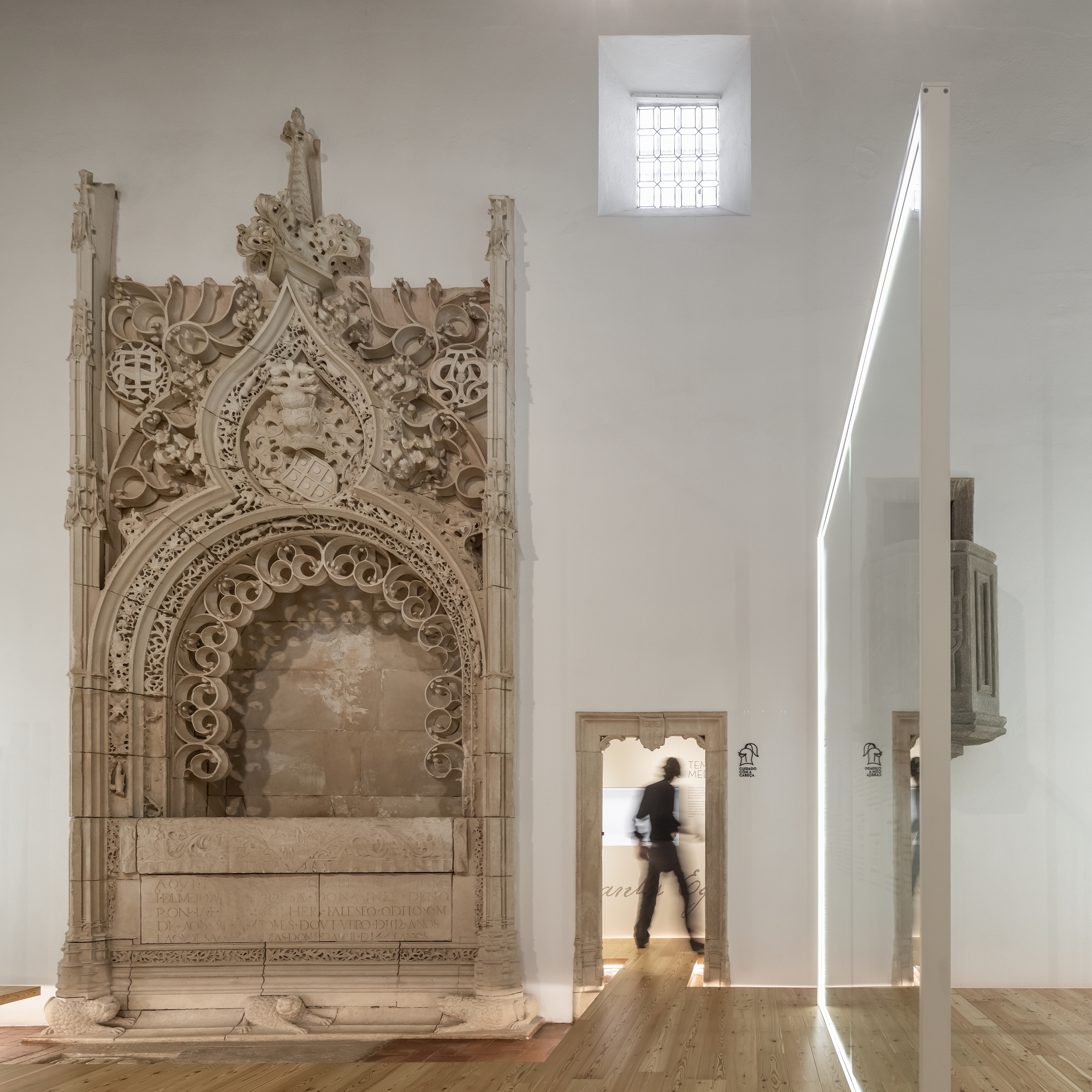 Carved stone portal beside doorway with person walking through backlit opening