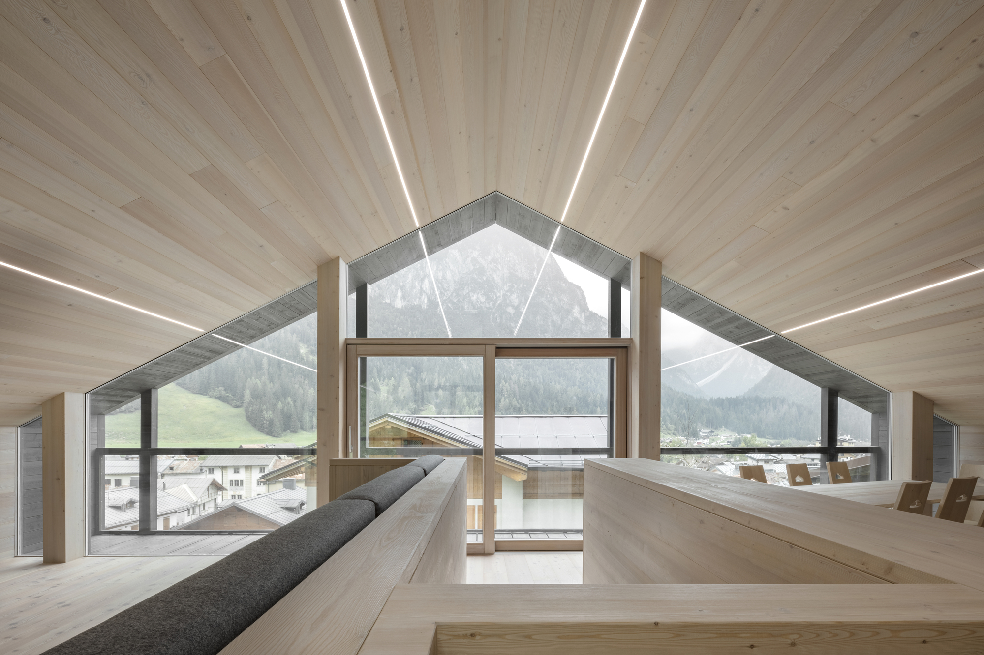 Attic room with gabled window framing mountain view and built-in benches along timber walls