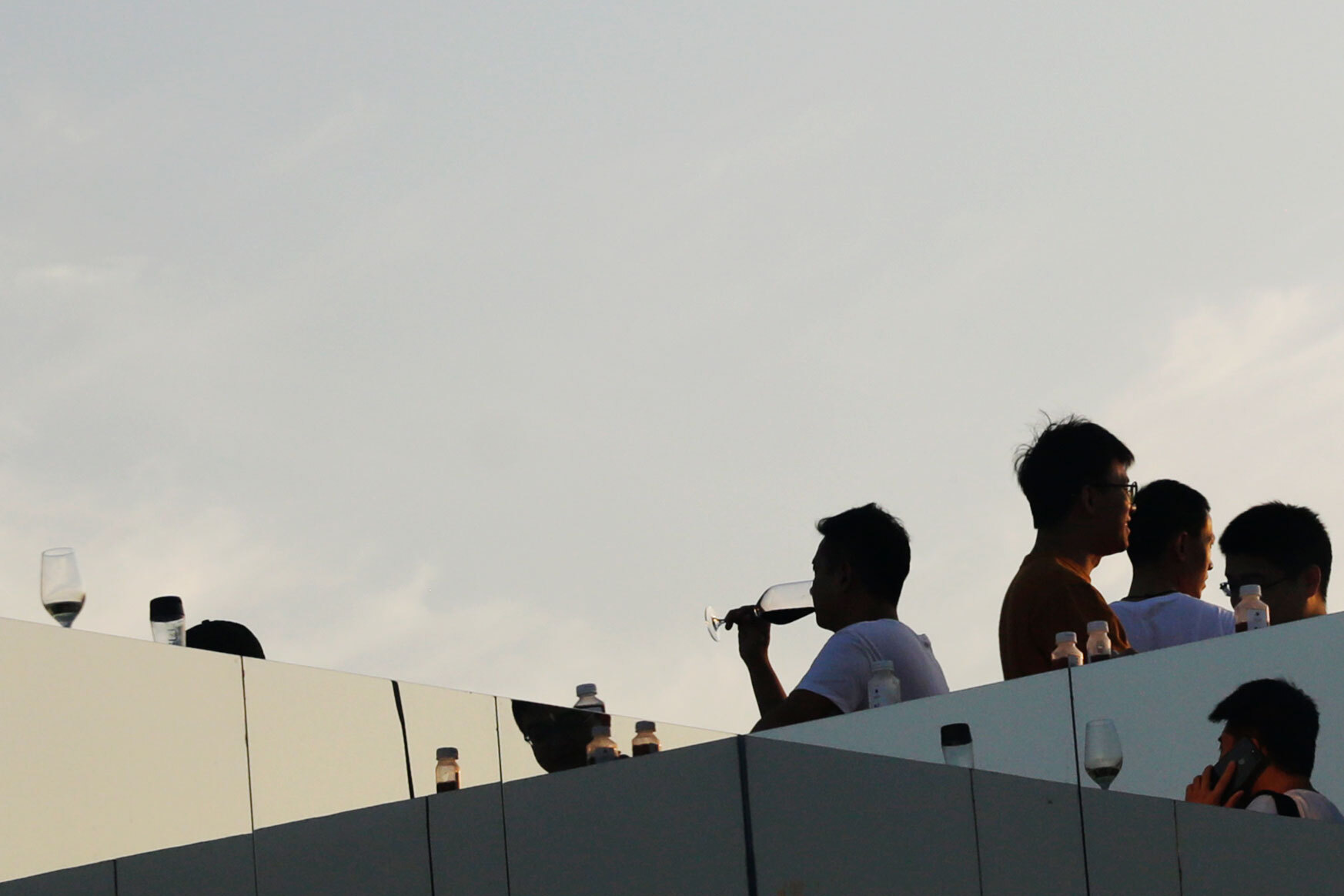 Frosted glass rooftop balustrade with figures silhouetted against the sunset sky