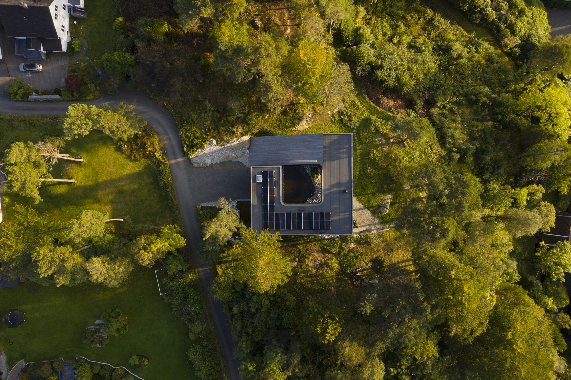Aerial view of the dark timber roof with central courtyard opening nestled among dense forest