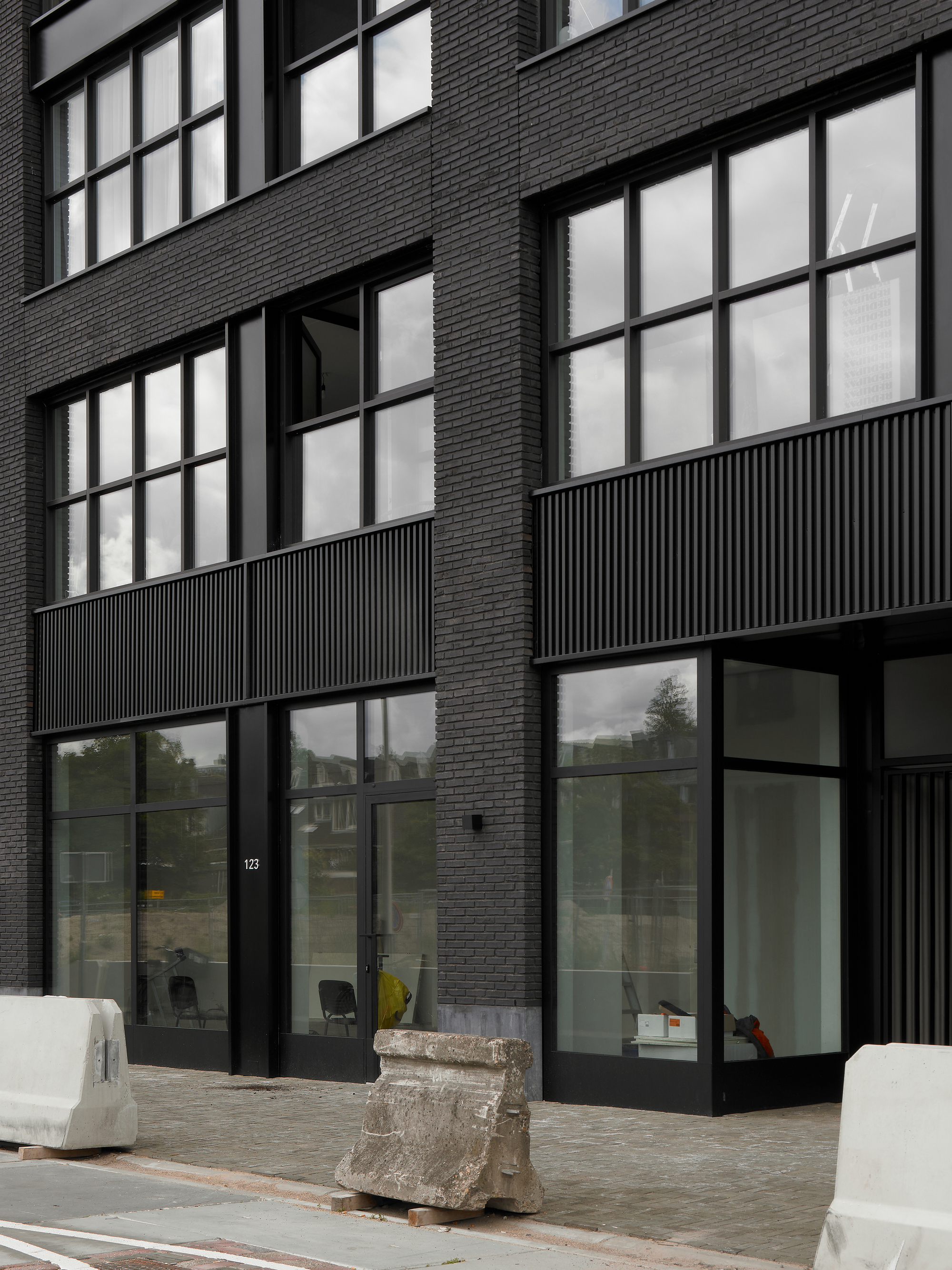 Ground floor entrance with black-framed glazing, fluted metal panels, and dark brick facade