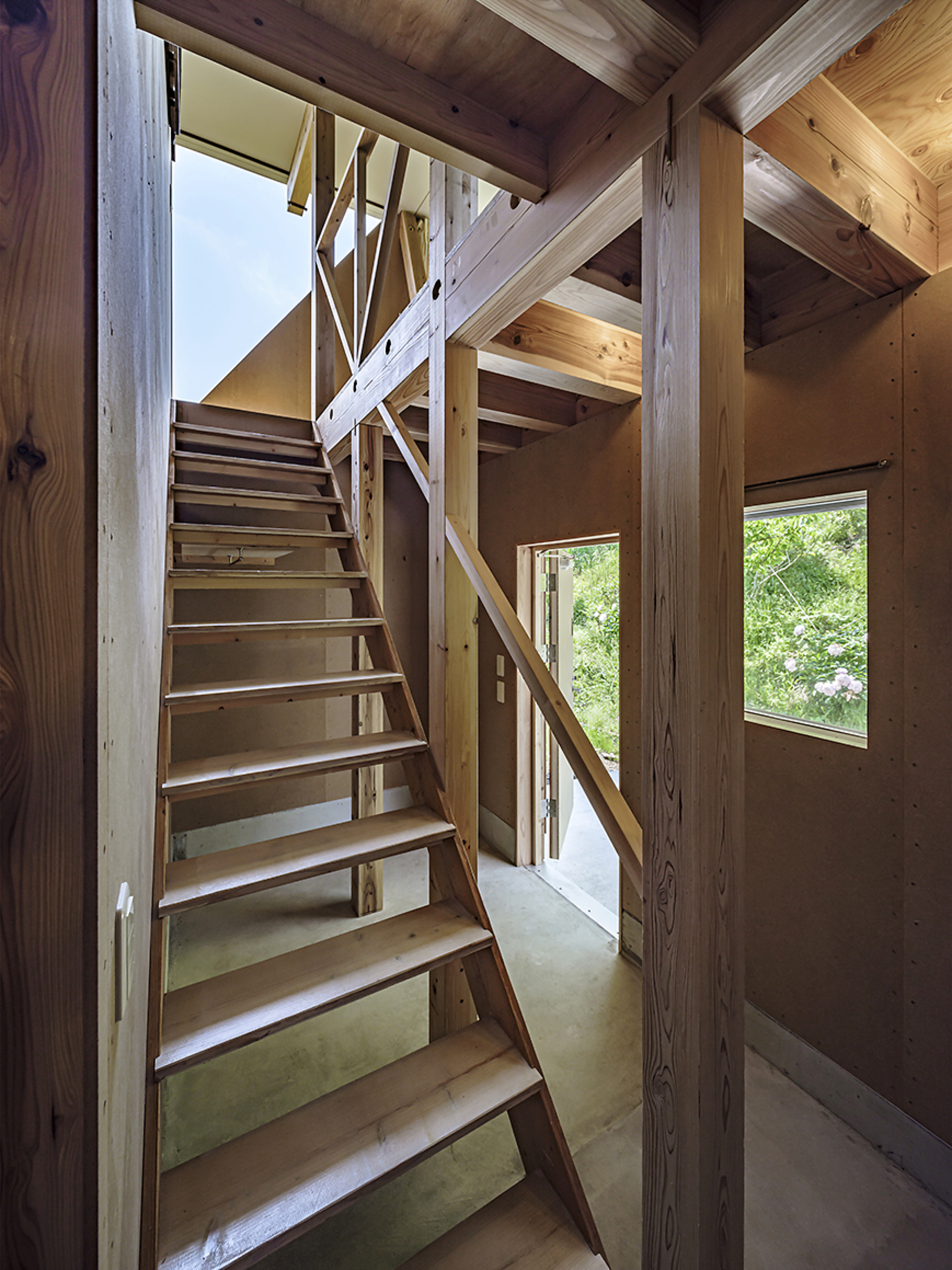 Open timber staircase with cross-braced railings ascending through a double-height space with exposed beams