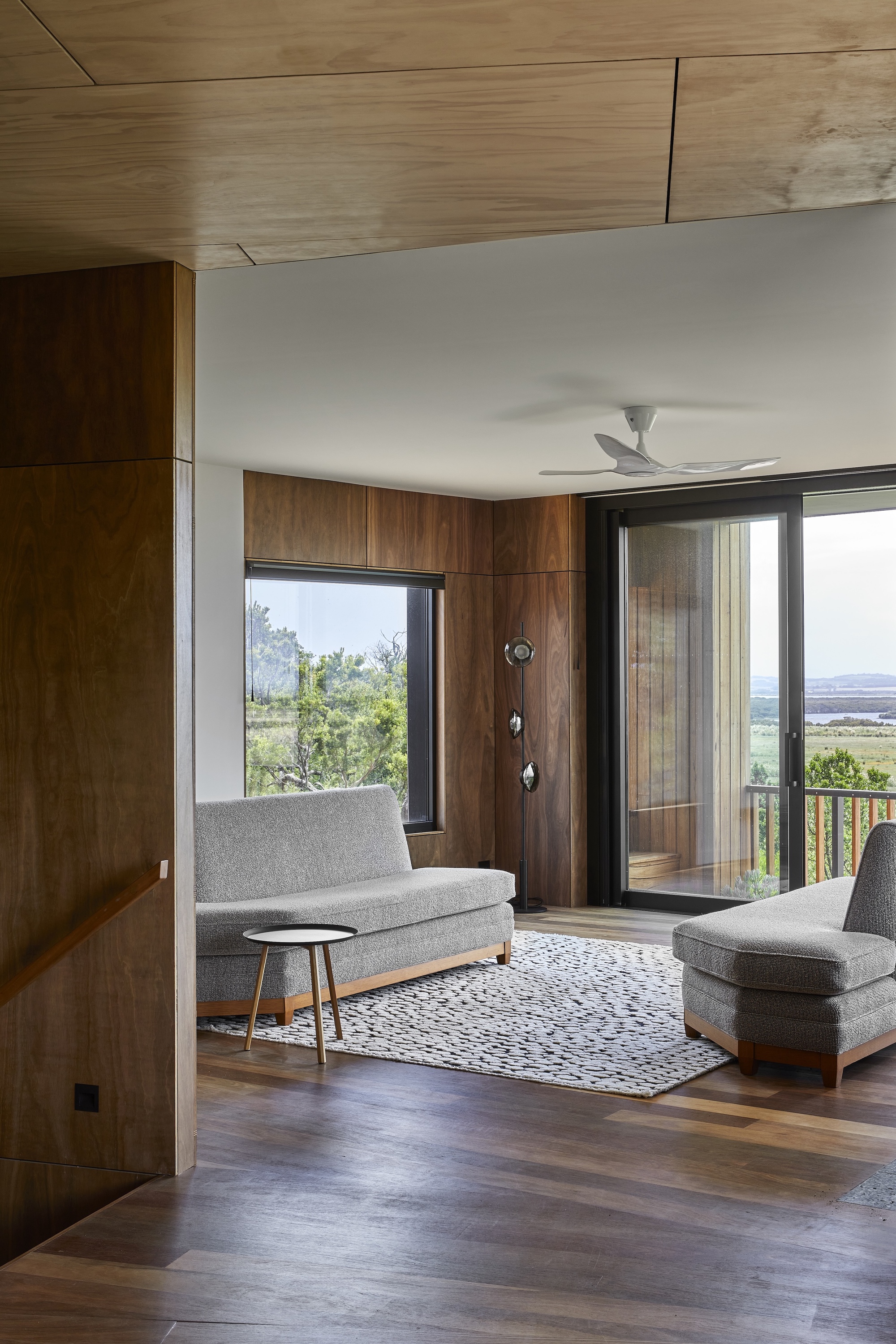 Living room with timber ceiling and floor-to-ceiling glazing framing coastal views