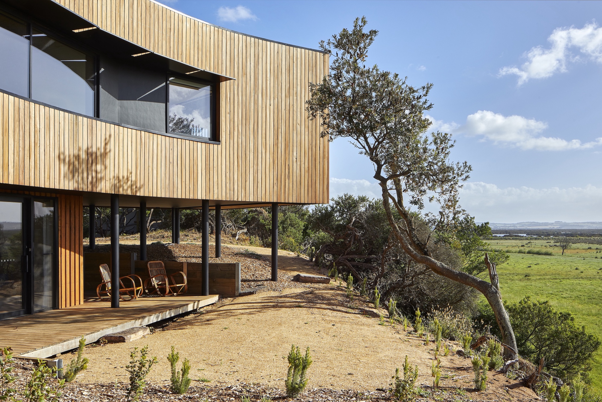 Timber deck wrapping around the glazed living space with views across the open landscape beyond