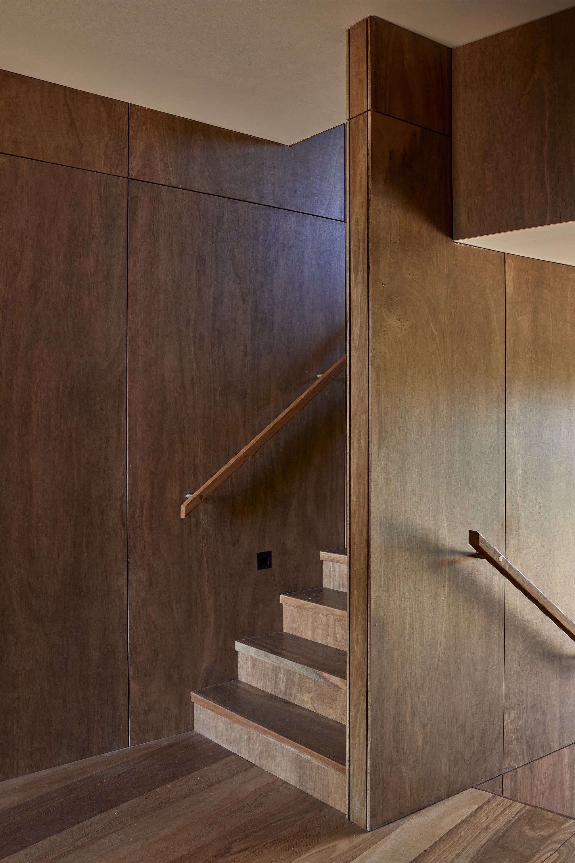Close view of the staircase corner where dark and light timber panels meet at a vertical edge