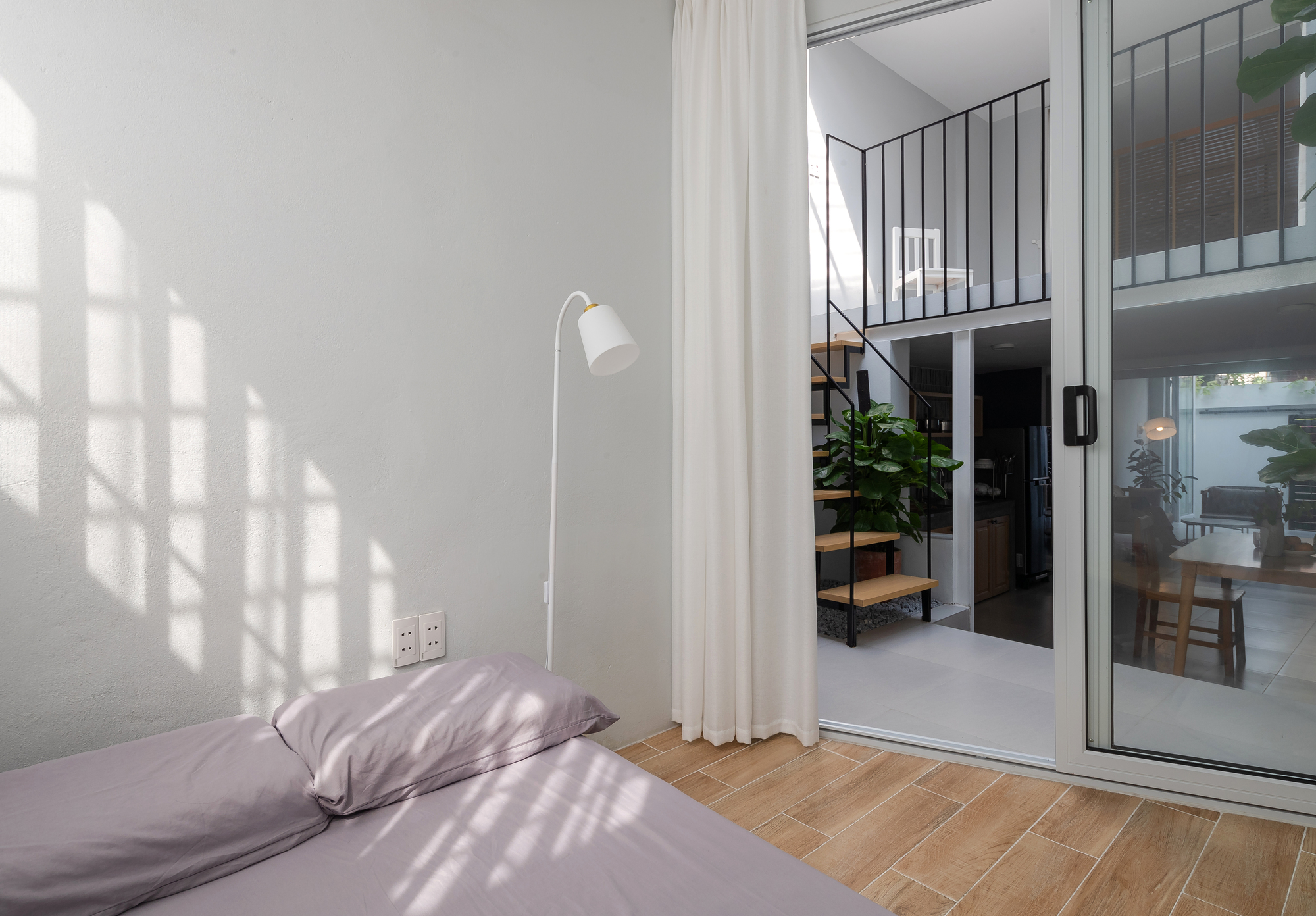 View from bedroom through sliding glass door to interior courtyard with timber shelving