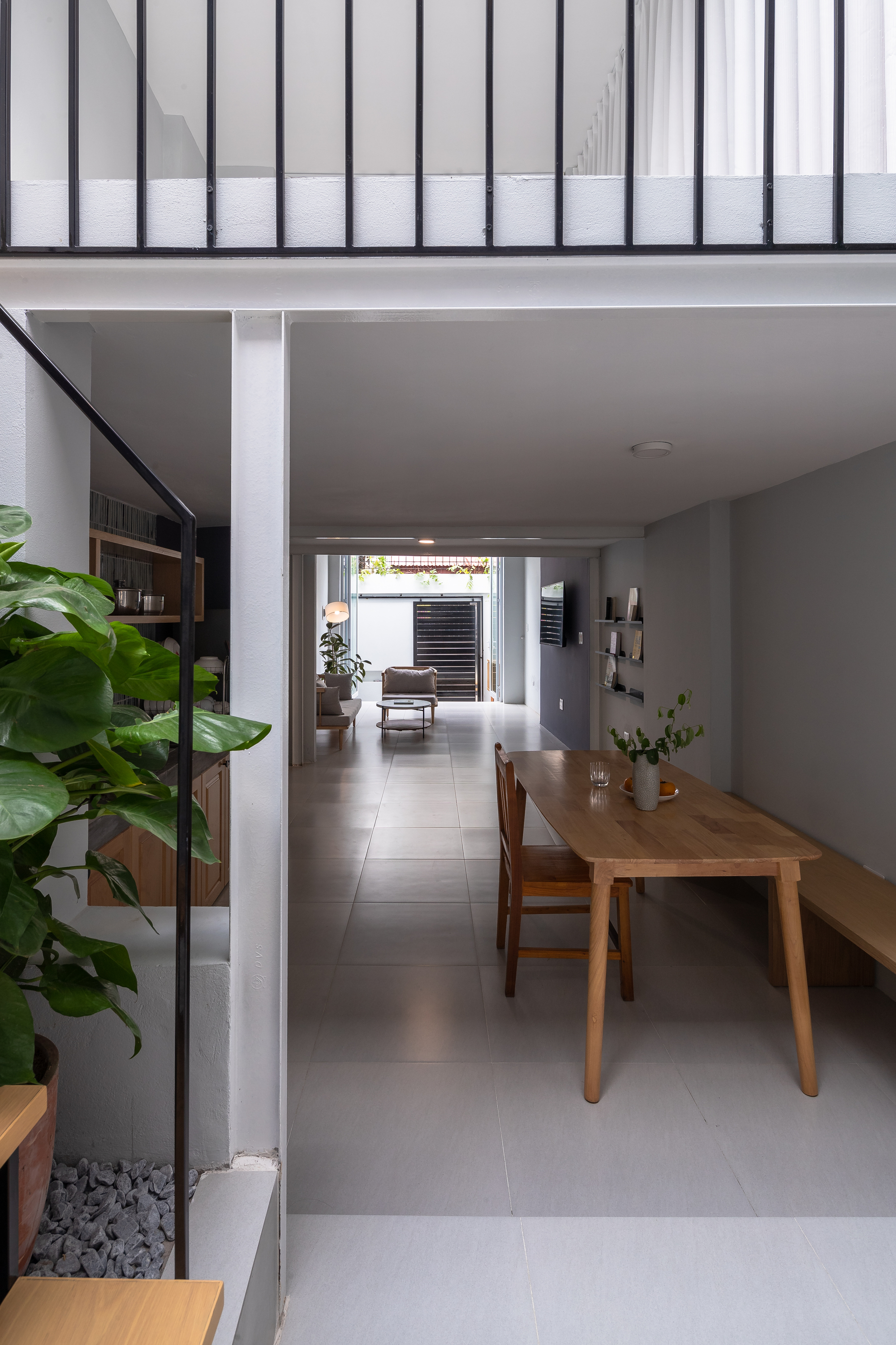 Open dining area with timber table and grey tile floor beneath a steel-framed clerestory window