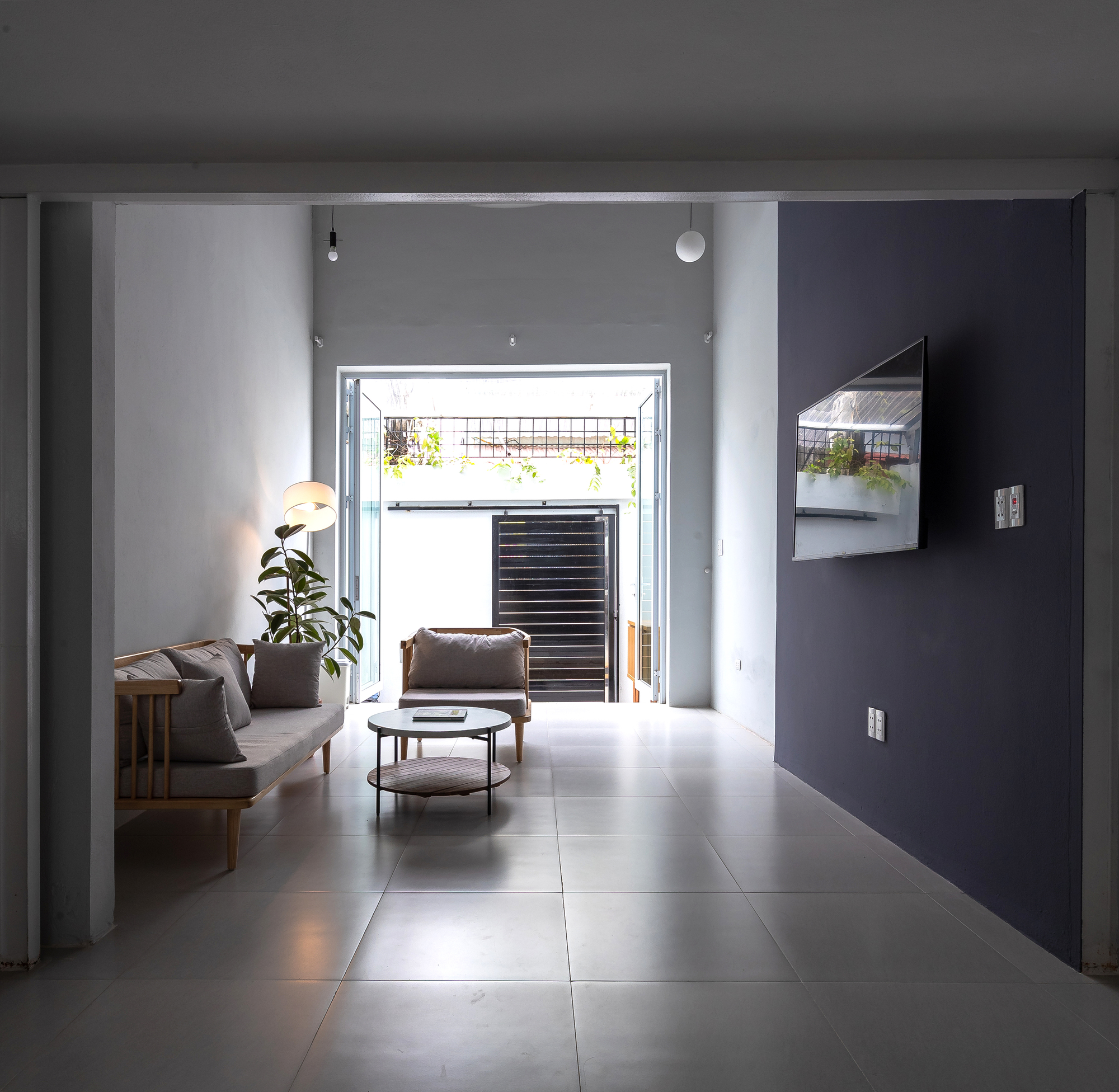 Living room with grey tile floor looking toward open doorway with louvered screening beyond
