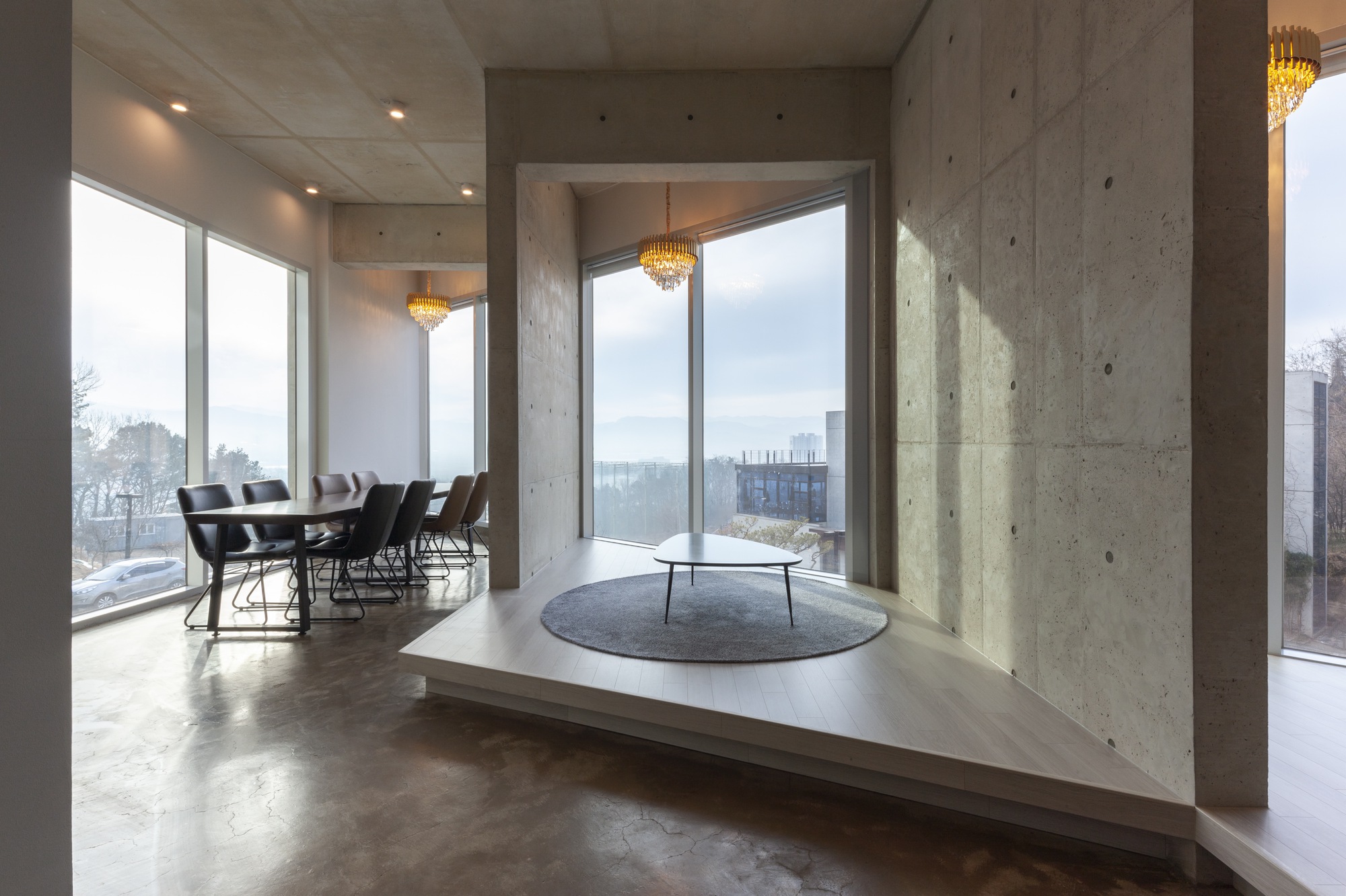 Raised platform seating area with concrete walls and corner windows overlooking winter landscape