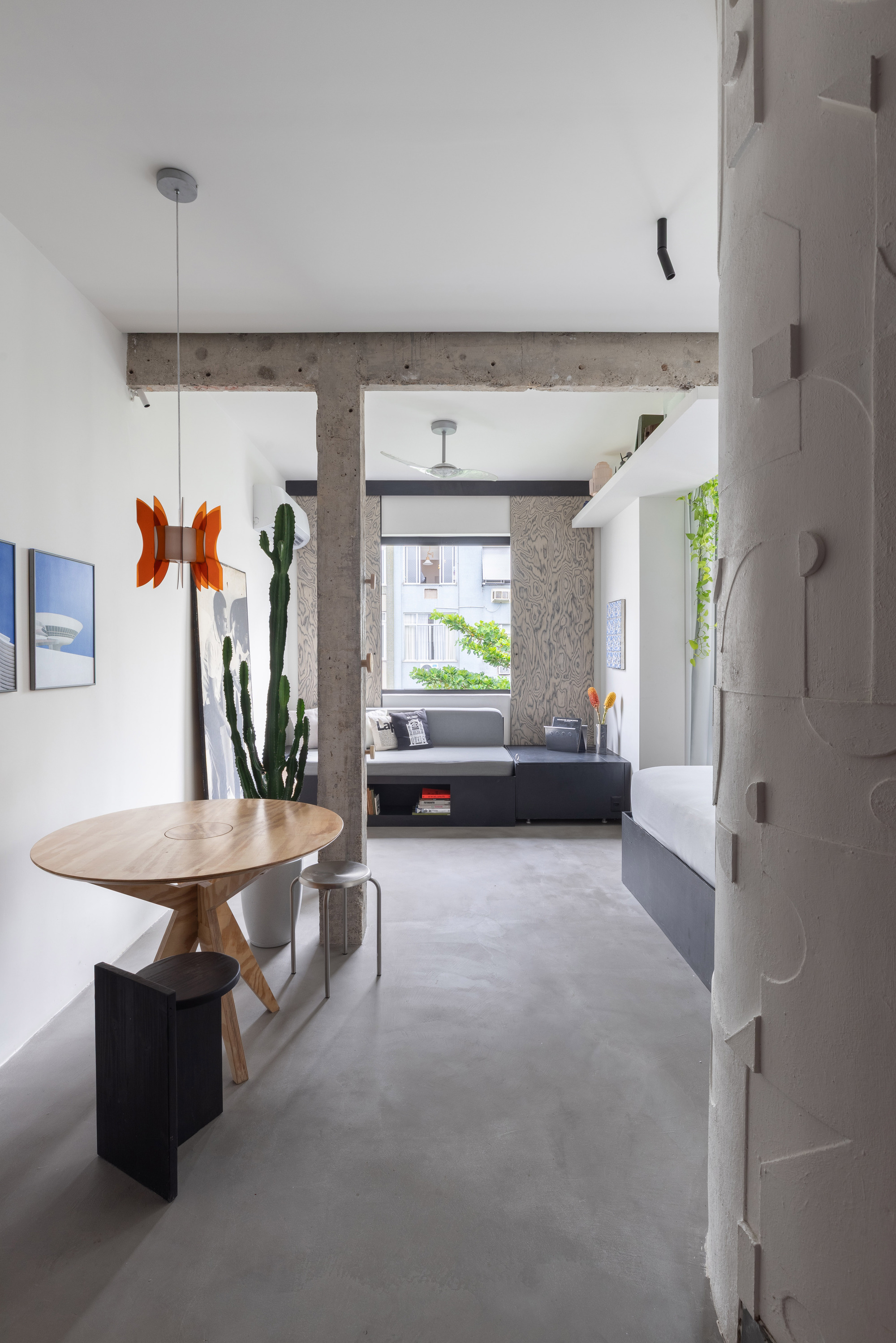Open living space framed by exposed concrete beams with polished concrete floors and potted cacti