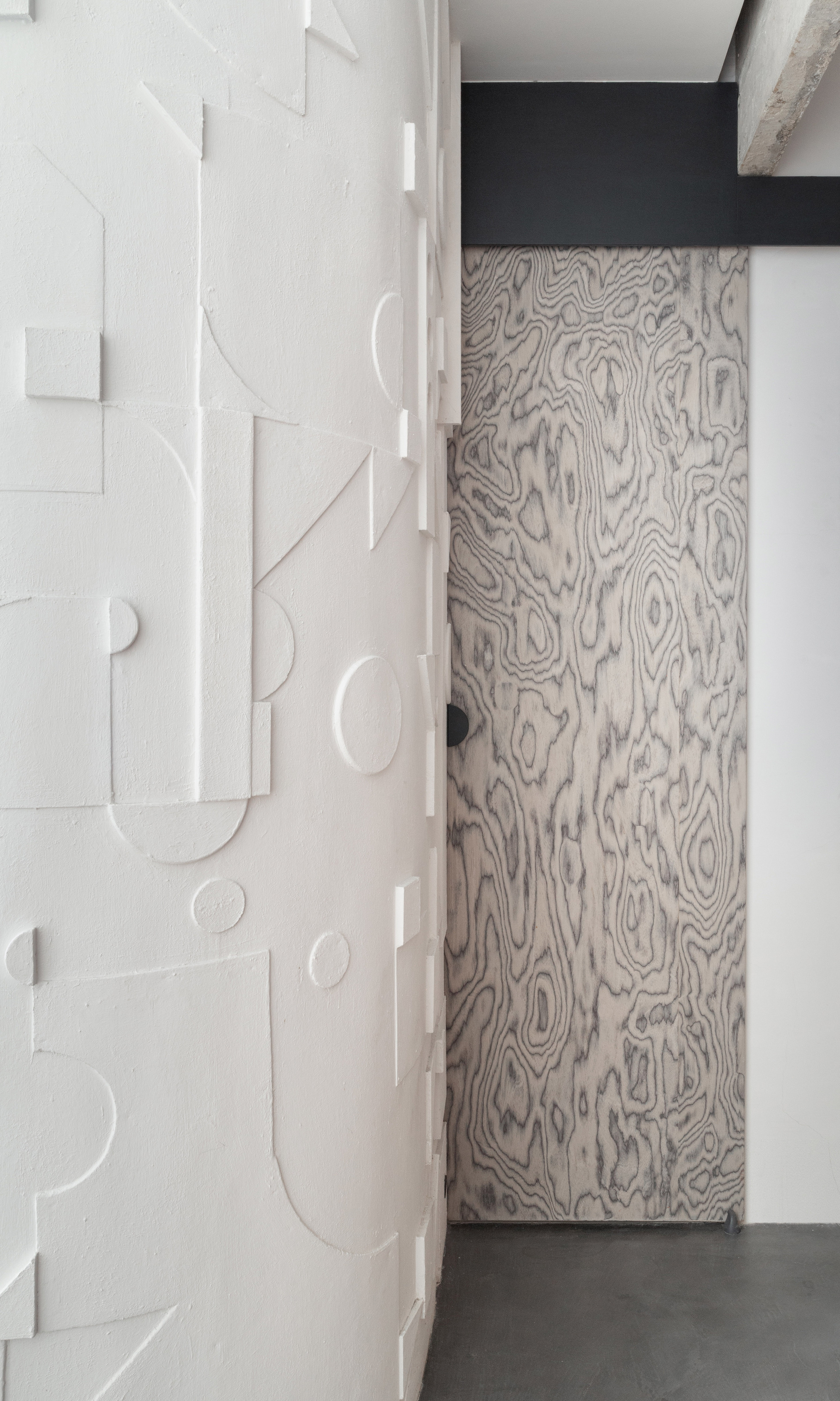 Close-up of wood grain sliding door next to white relief panel wall