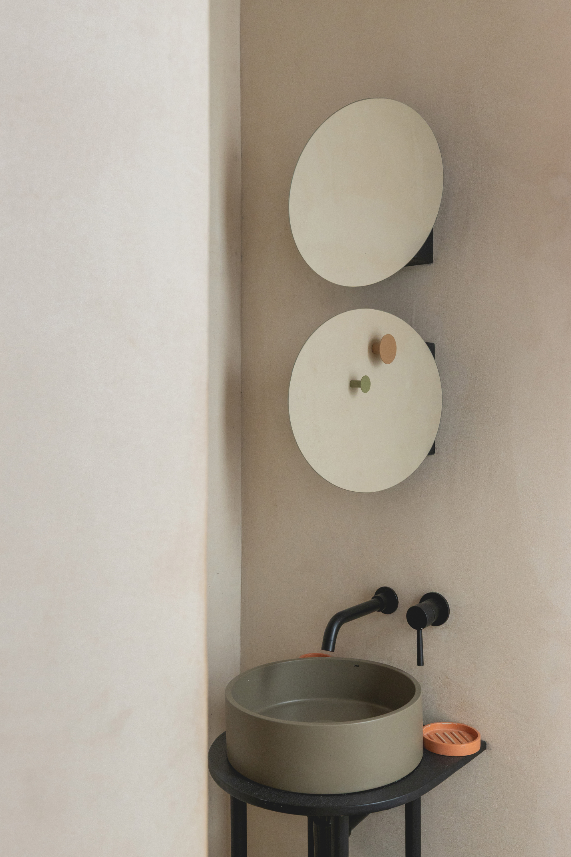 Bathroom vanity with round sage basin on black stand and matte black wall-mounted fixtures