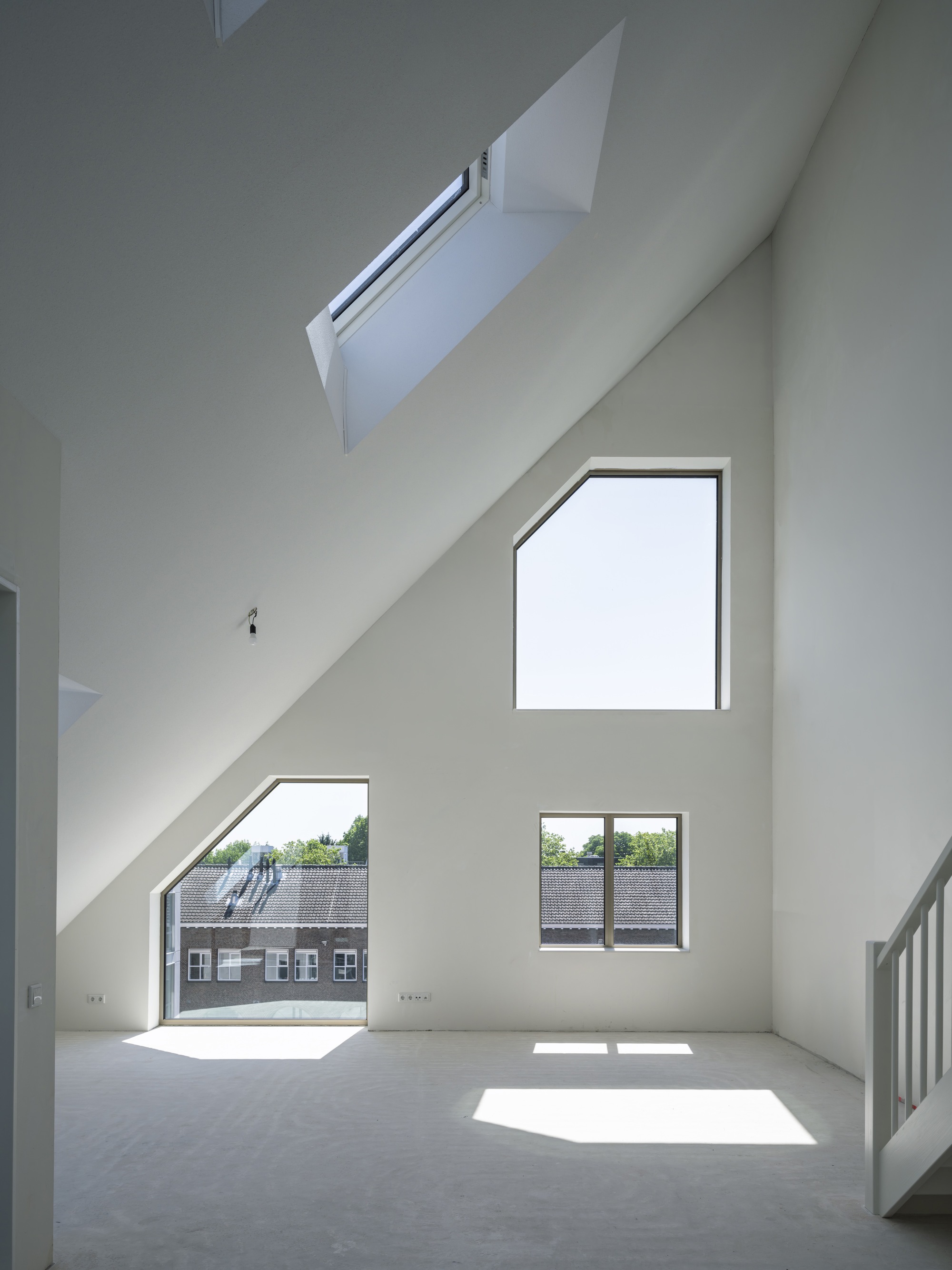 Double-height interior space with slanted walls and scattered pentagonal windows casting sunlight across the floor