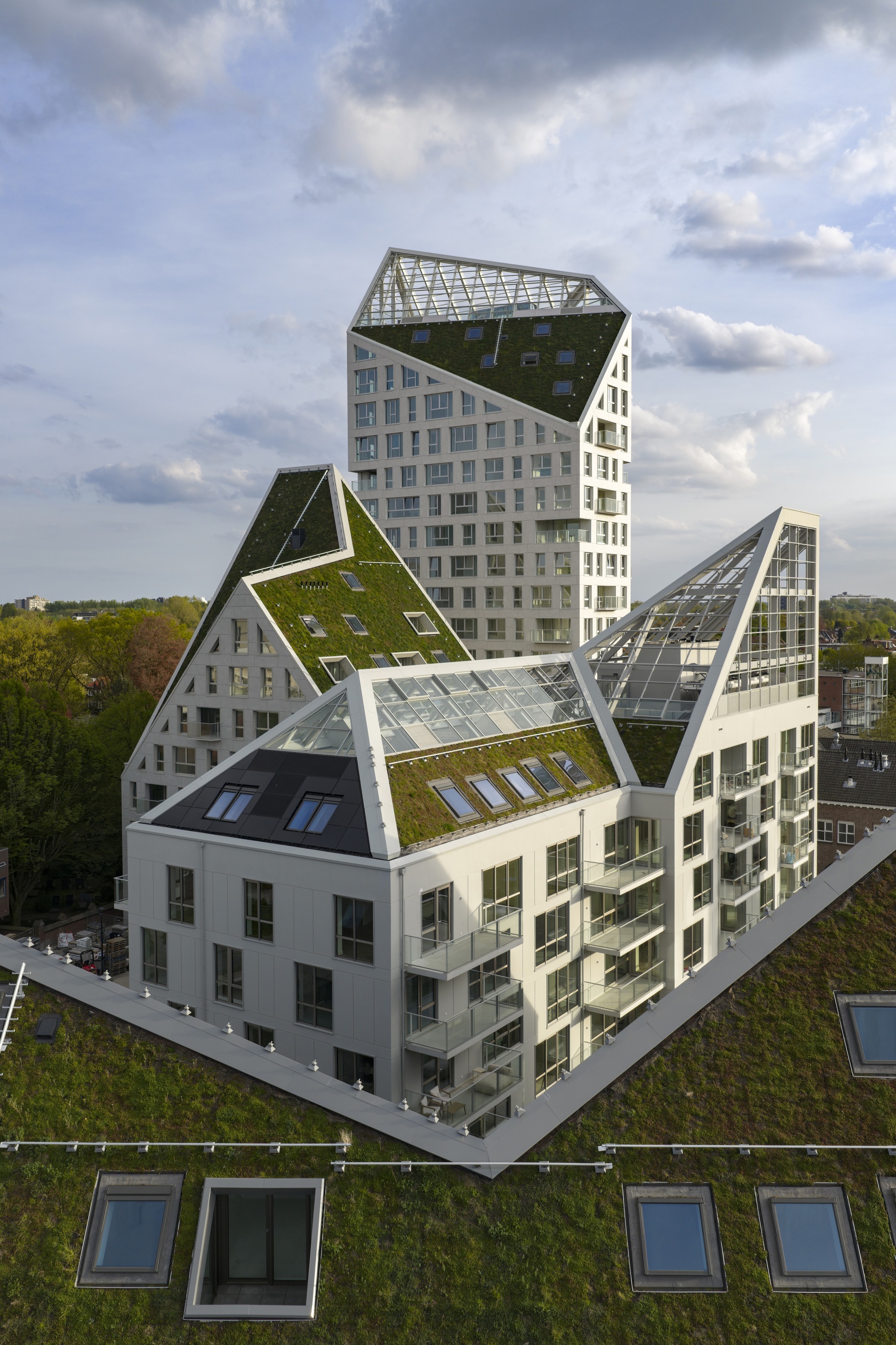 Aerial view of stacked green roofs and glazed gables above terraced residential volumes