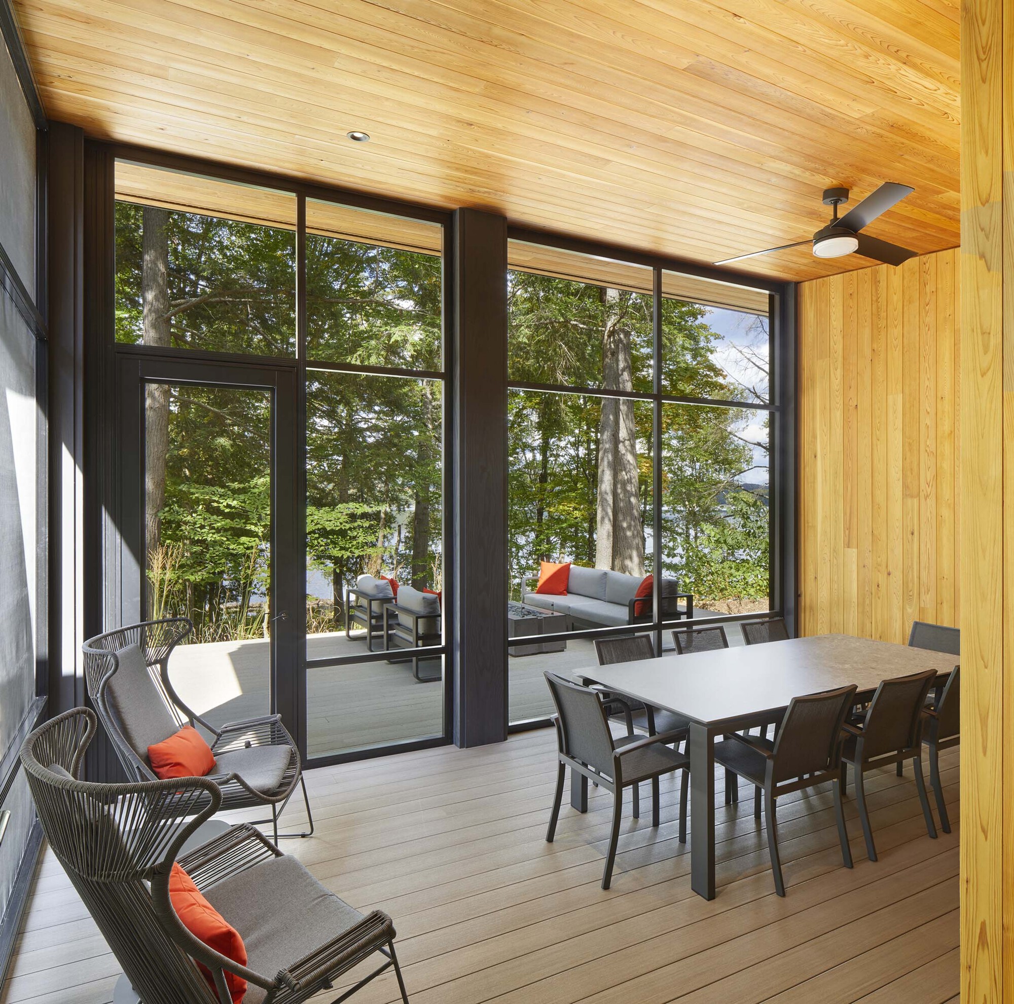 Screened porch with composite decking, timber ceiling, and steel-framed glazing overlooking the forest