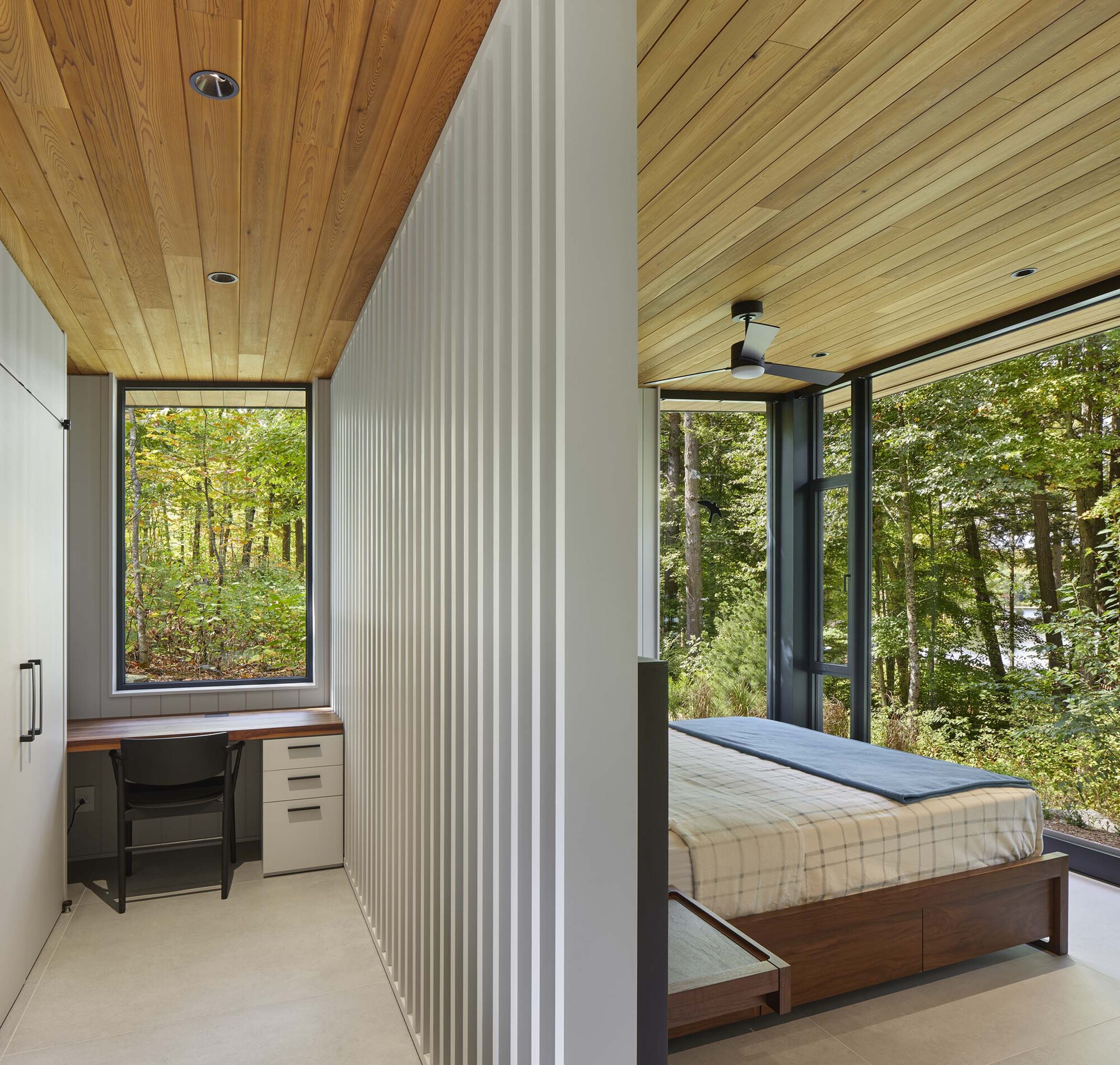 Bedroom with white vertical panel partition separating sleeping area from workspace under a timber ceiling