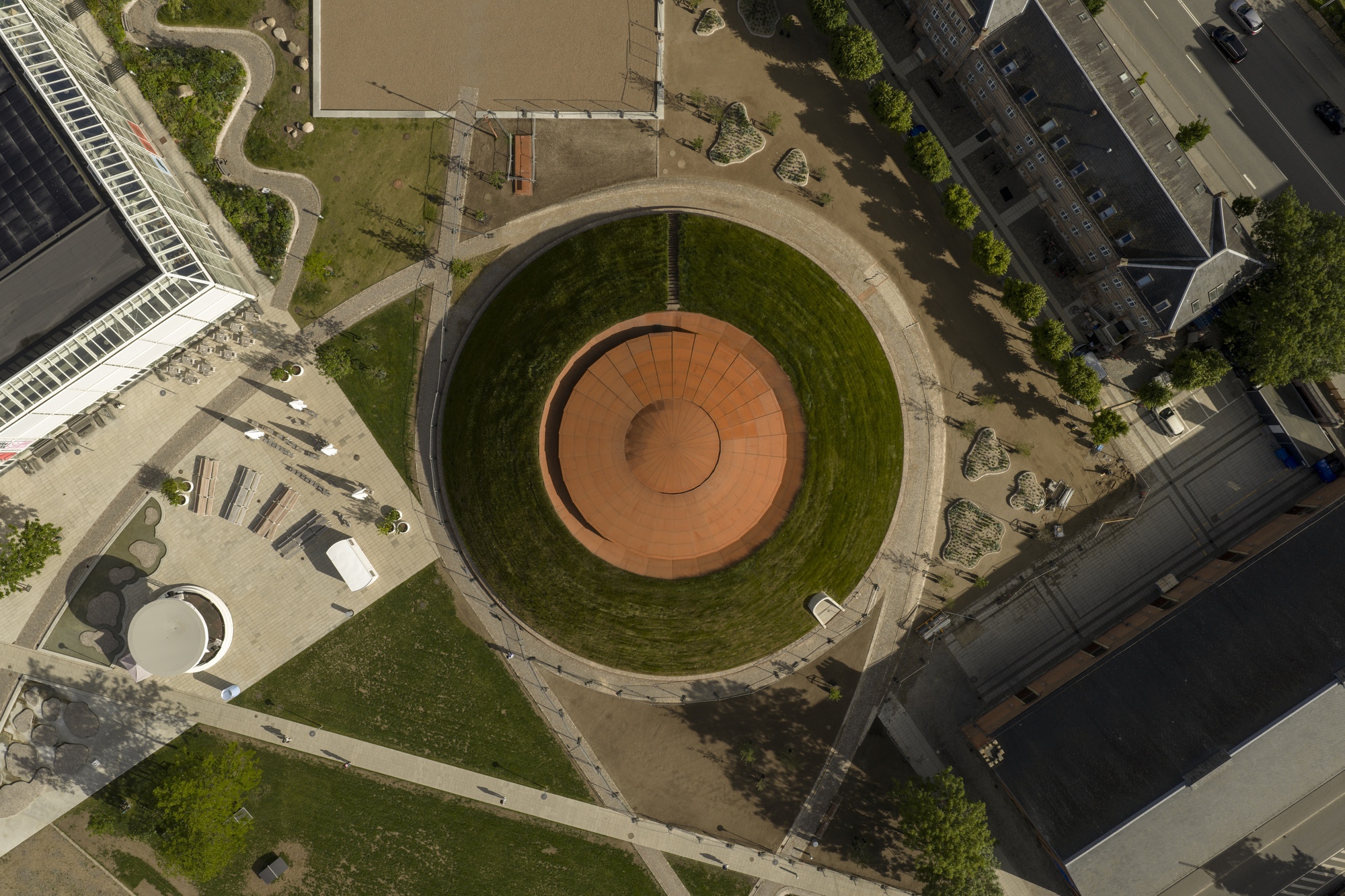 Aerial view of the circular rooftop plaza with concentric rings of terracotta paving and grassy slopes