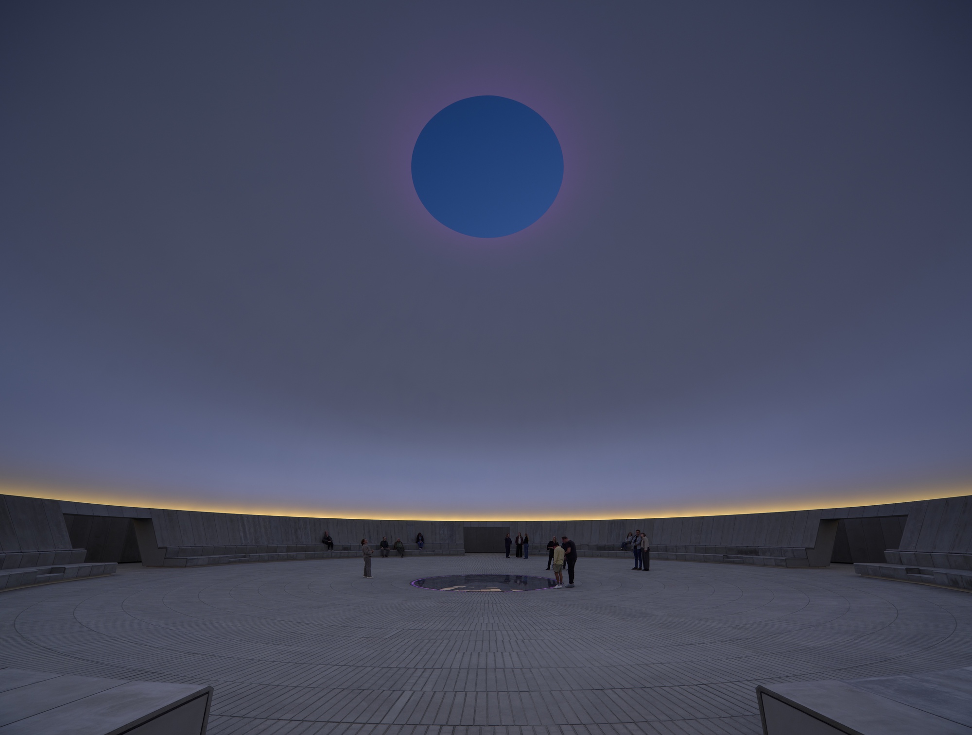 Interior view of the circular courtyard with central oculus and visitors gathering at dusk