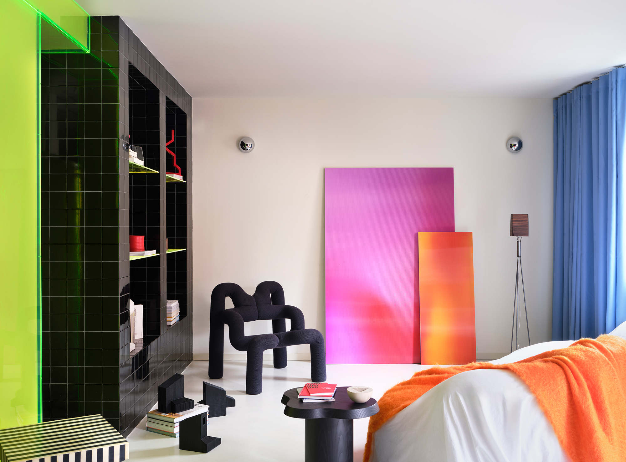 Interior bedroom with black tiled shelving, gradient resin panels, and a sculptural foam chair
