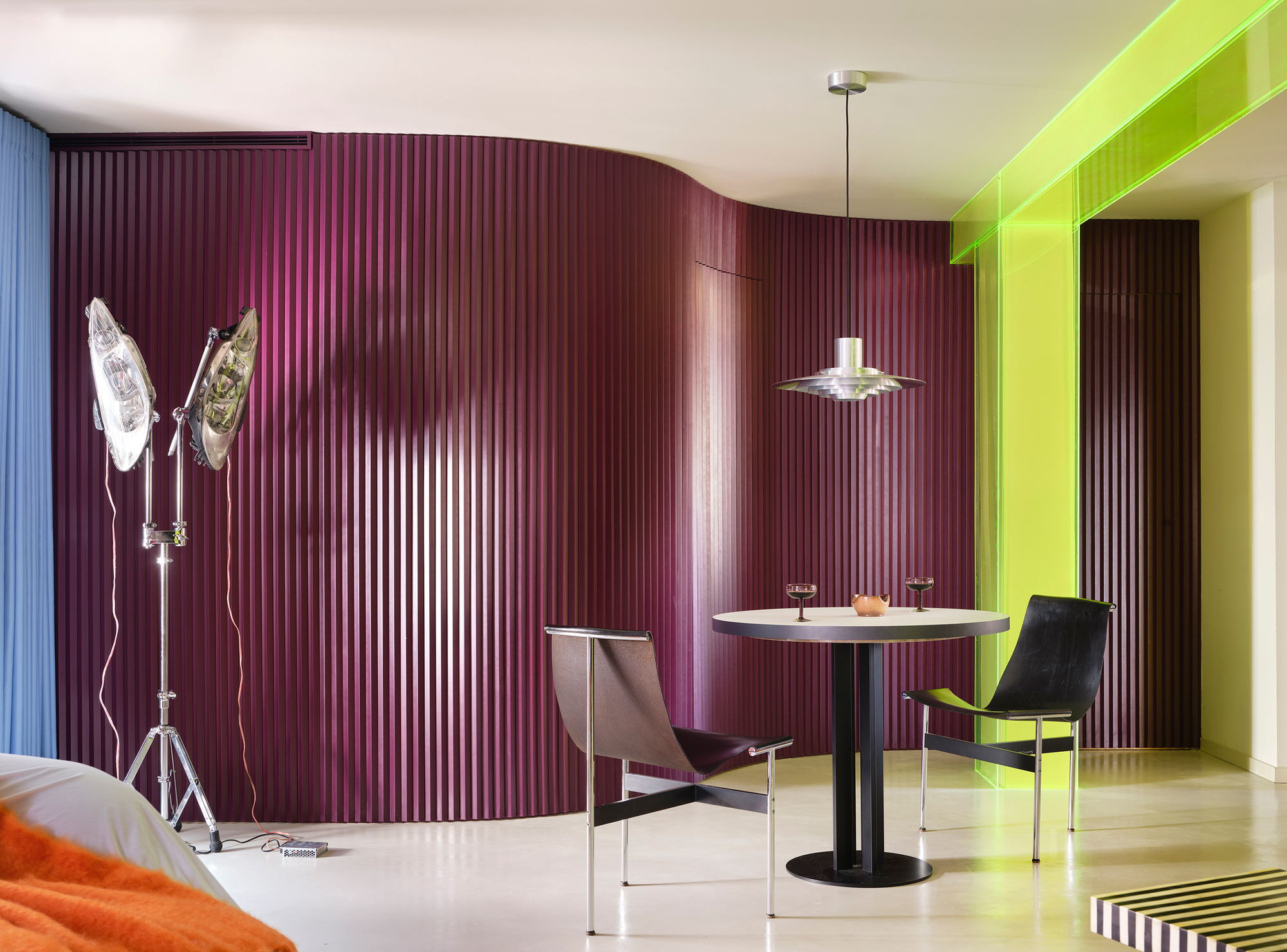 Dining area with curved maroon fluted wall panels and lime green framed passageway