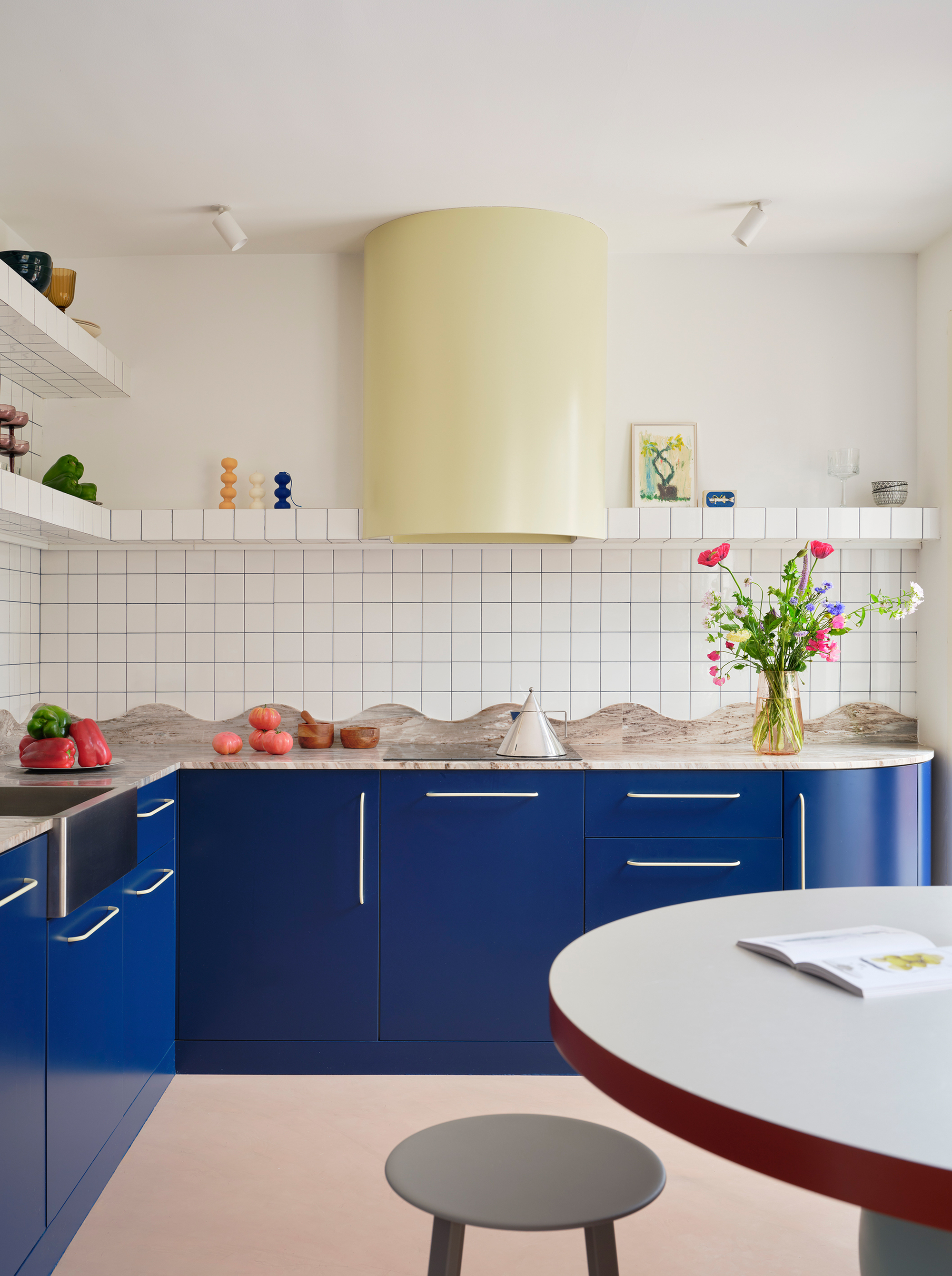 Kitchen with blue lacquered cabinets, white grid tile backsplash, and fresh flowers on the counter