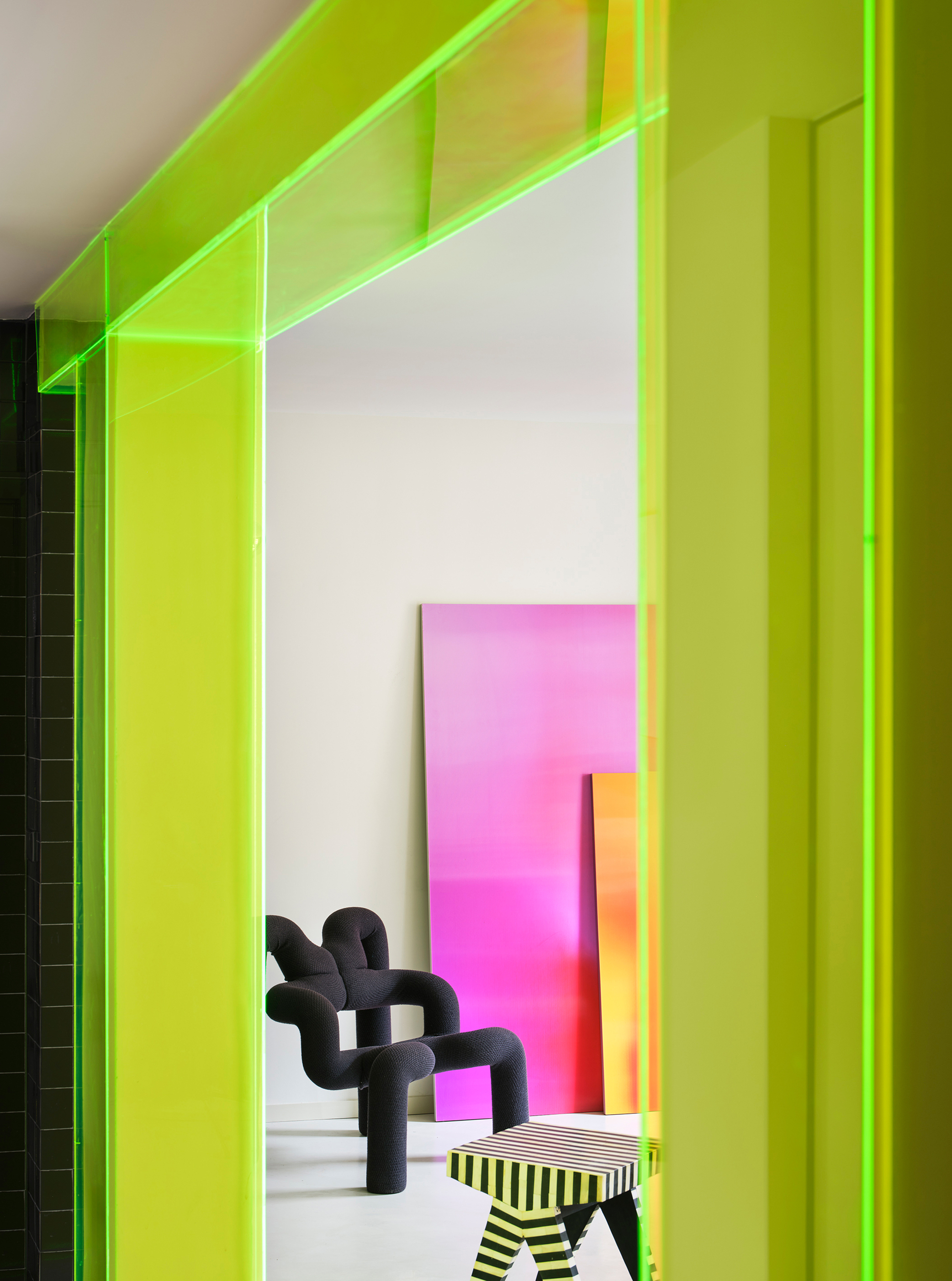 Doorway framed by lime green acrylic panels looking into a room with gradient artworks
