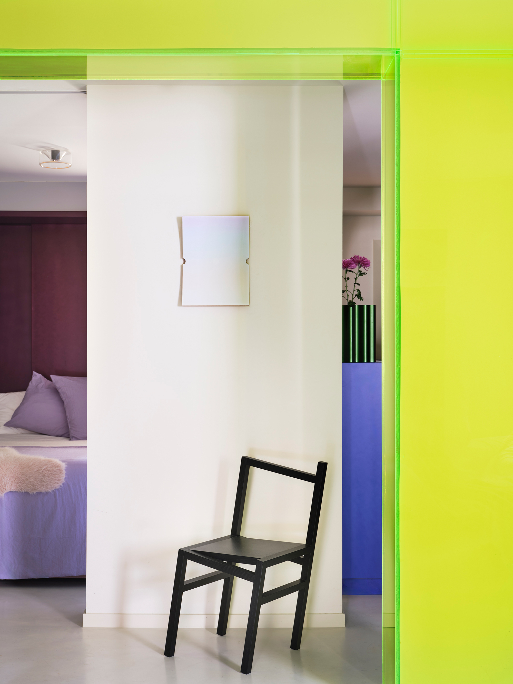 Black chair against white wall framed by a bright lime green doorway with view into adjacent rooms