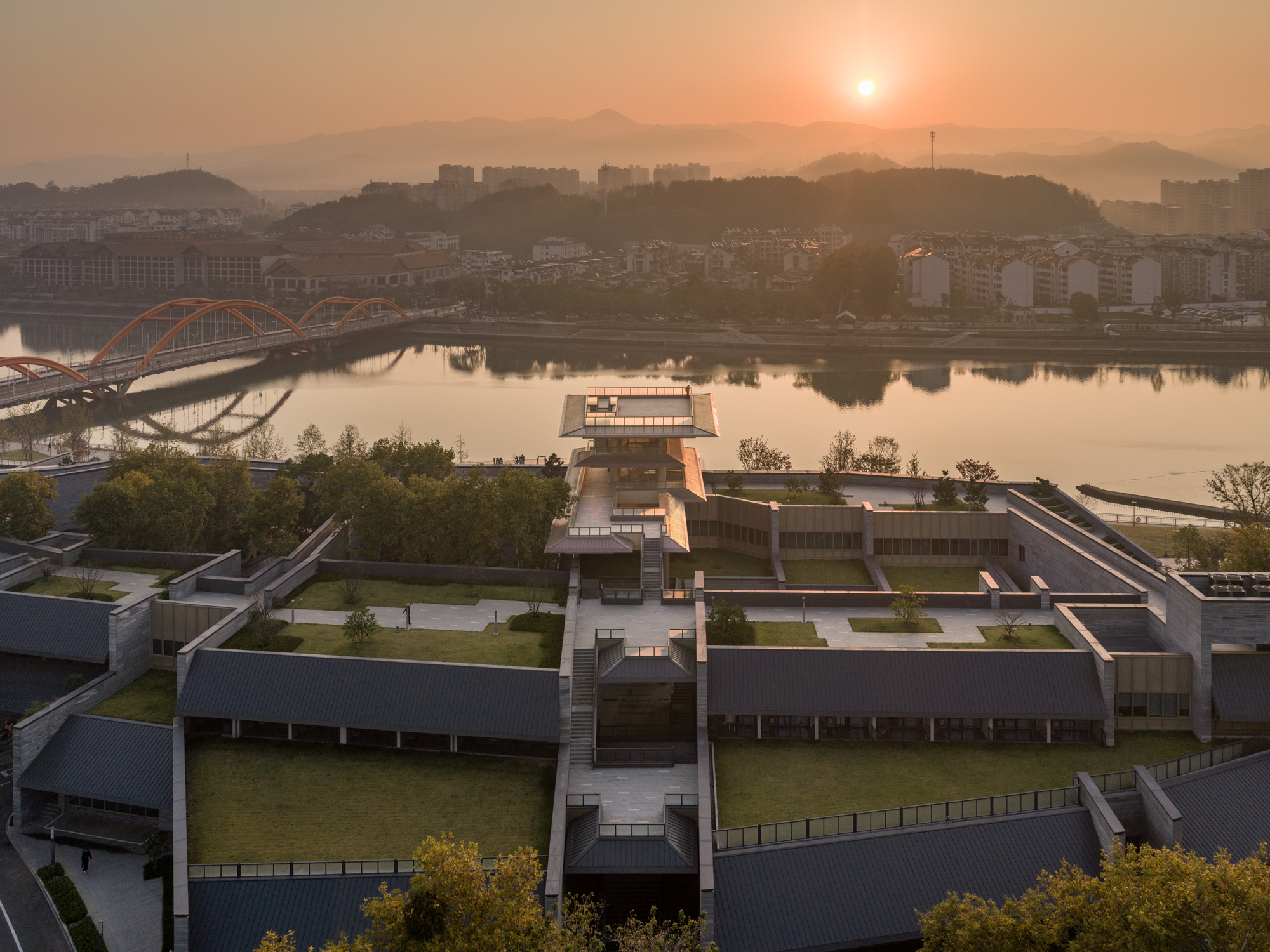 Aerial view of the low-rise complex with green roofs beside the river at sunset