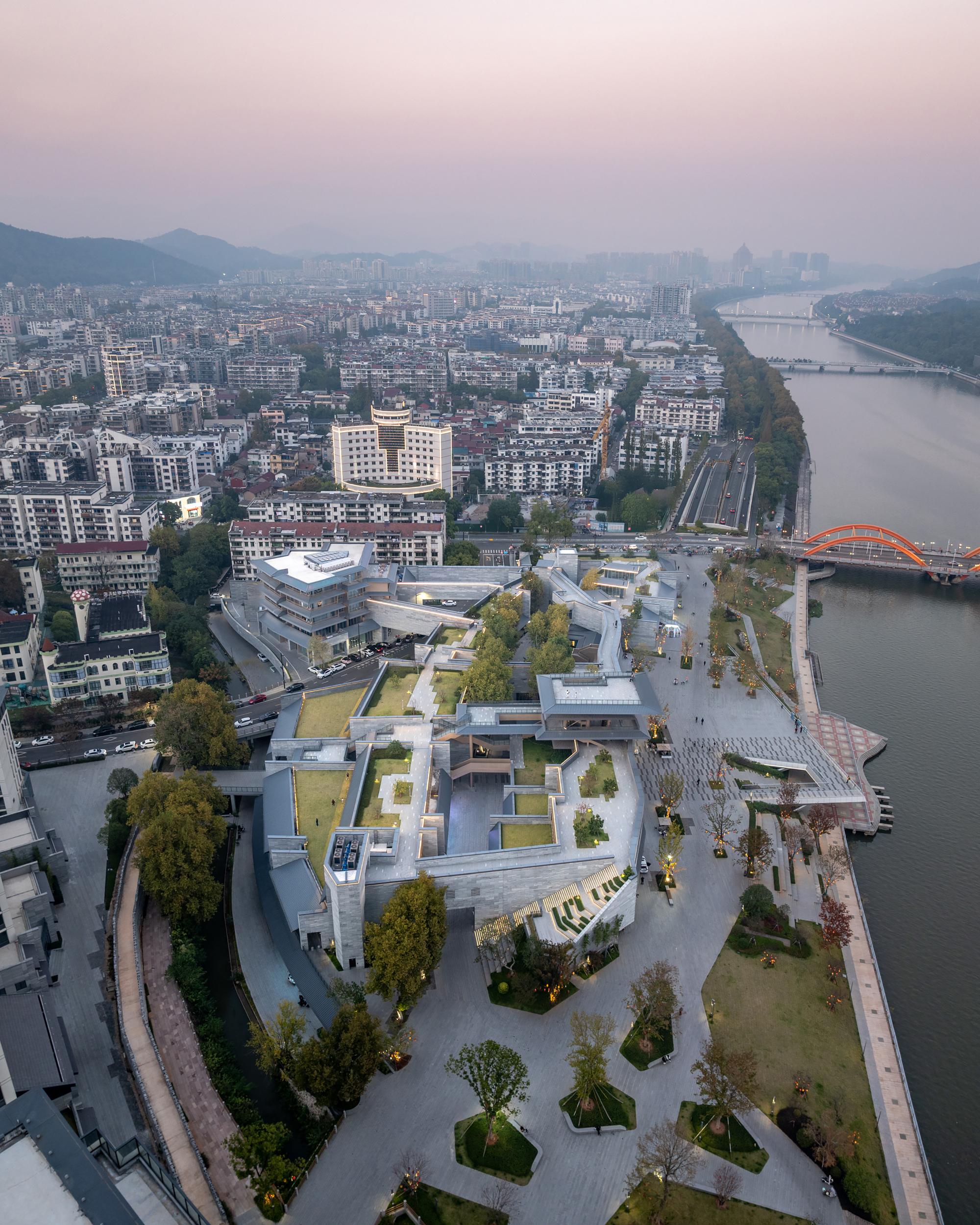 Drone view of the terraced rooftop gardens and plazas along the riverside at dusk