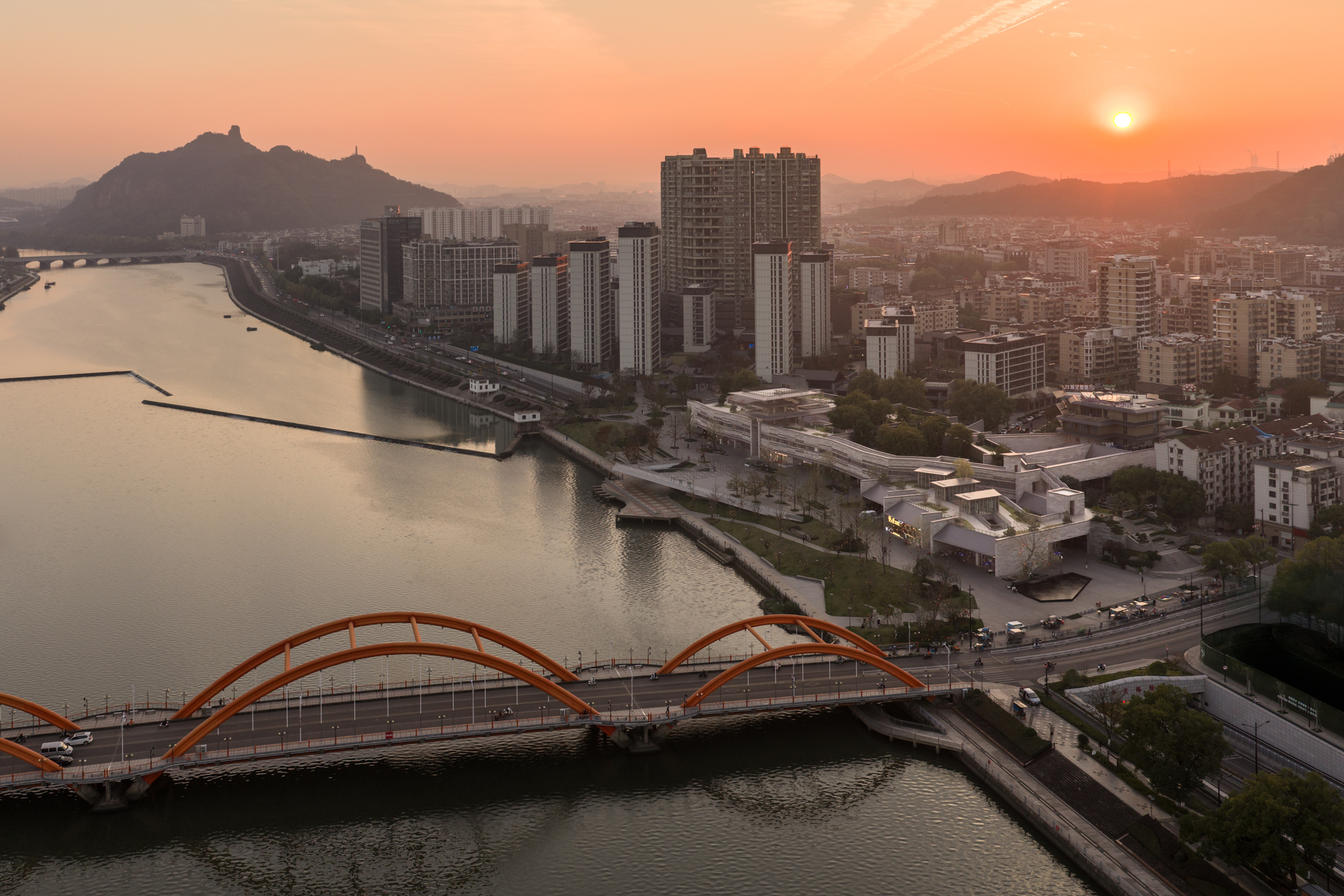 Aerial view of the red arched pedestrian bridge spanning the river at sunset